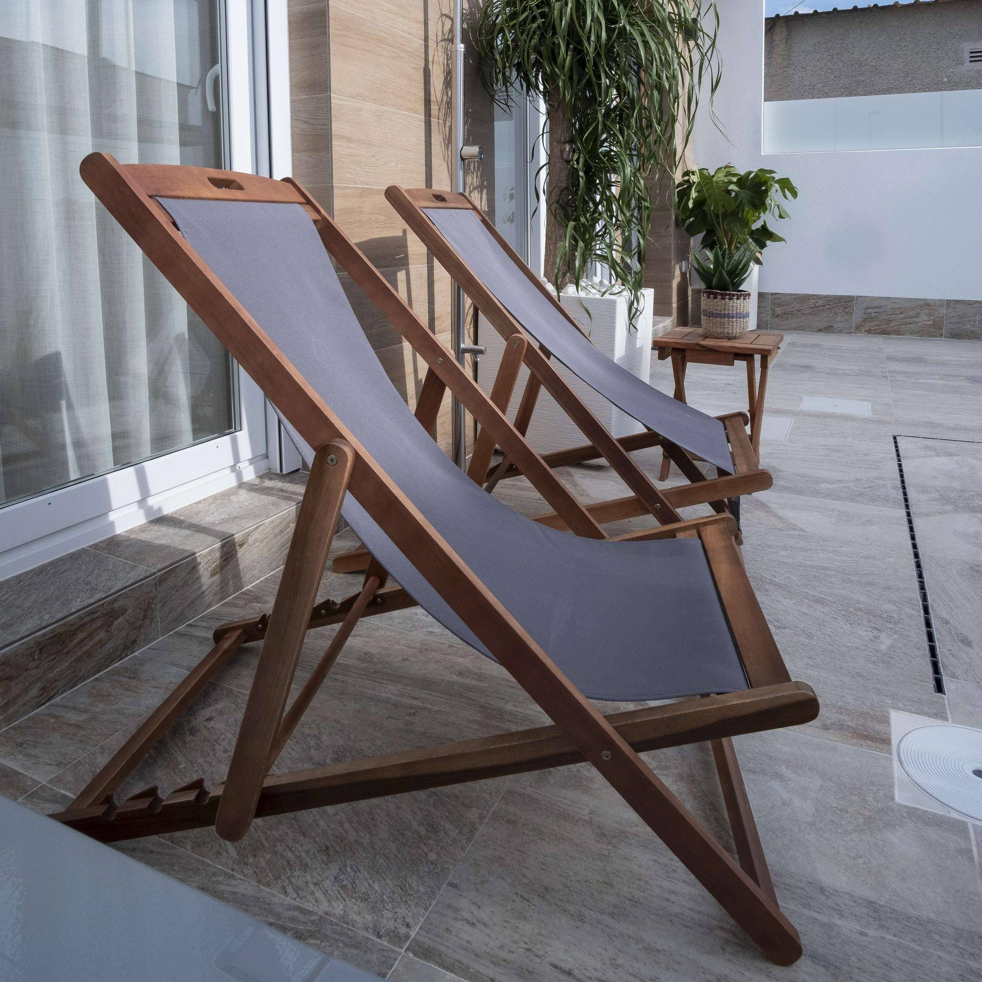 Bequeme Liegestühle auf der gefliesten Terrasse, ideal zum Entspannen am Pool.
