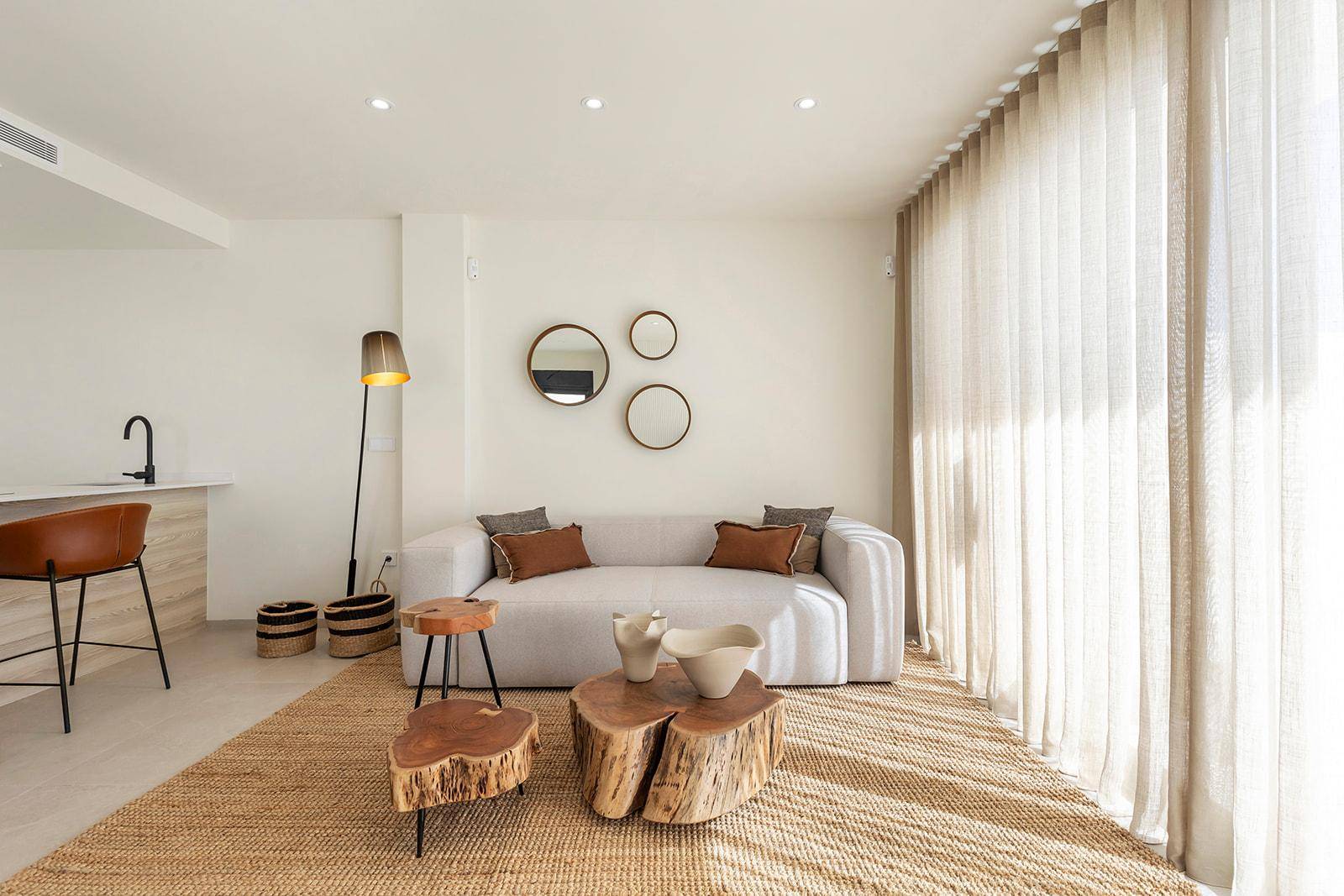 Helles Wohnzimmer mit bequemer Couch, Holztischen und großen Fenstern für viel Tageslicht.