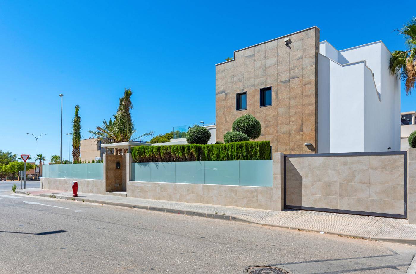 Moderne Villa von der Straße aus gesehen mit eleganter Fassade und umzäuntem Grundstück.