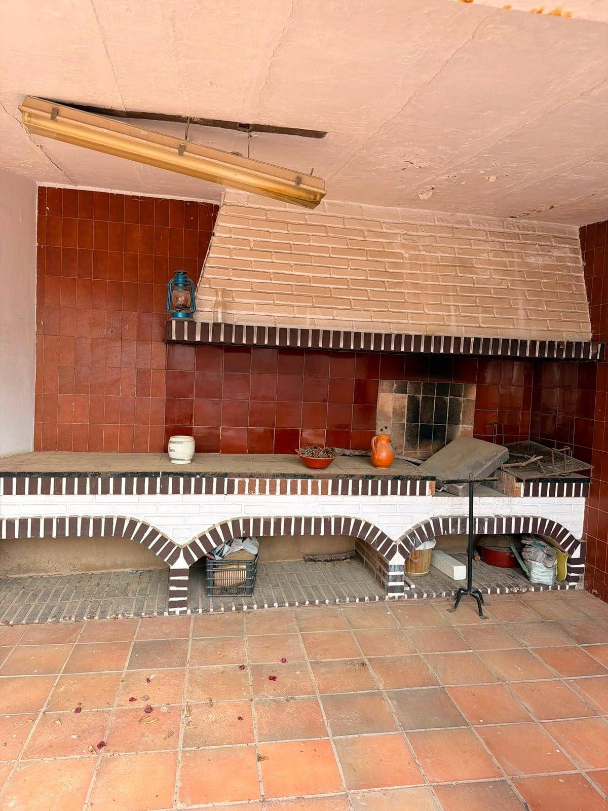 Überdachter Grillbereich mit gemauertem Grill und Arbeitsfläche, ideal für Mahlzeiten im Freien.