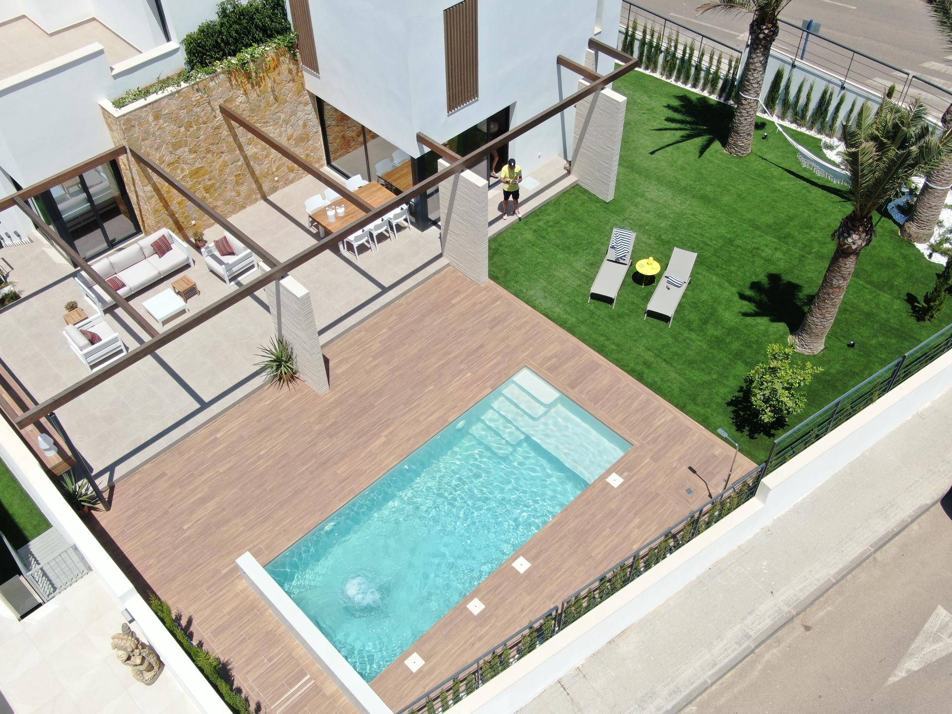 Vogelperspektive der modernen Villa mit großem Pool, Holzterrasse und weitläufigem Gartenbereich.