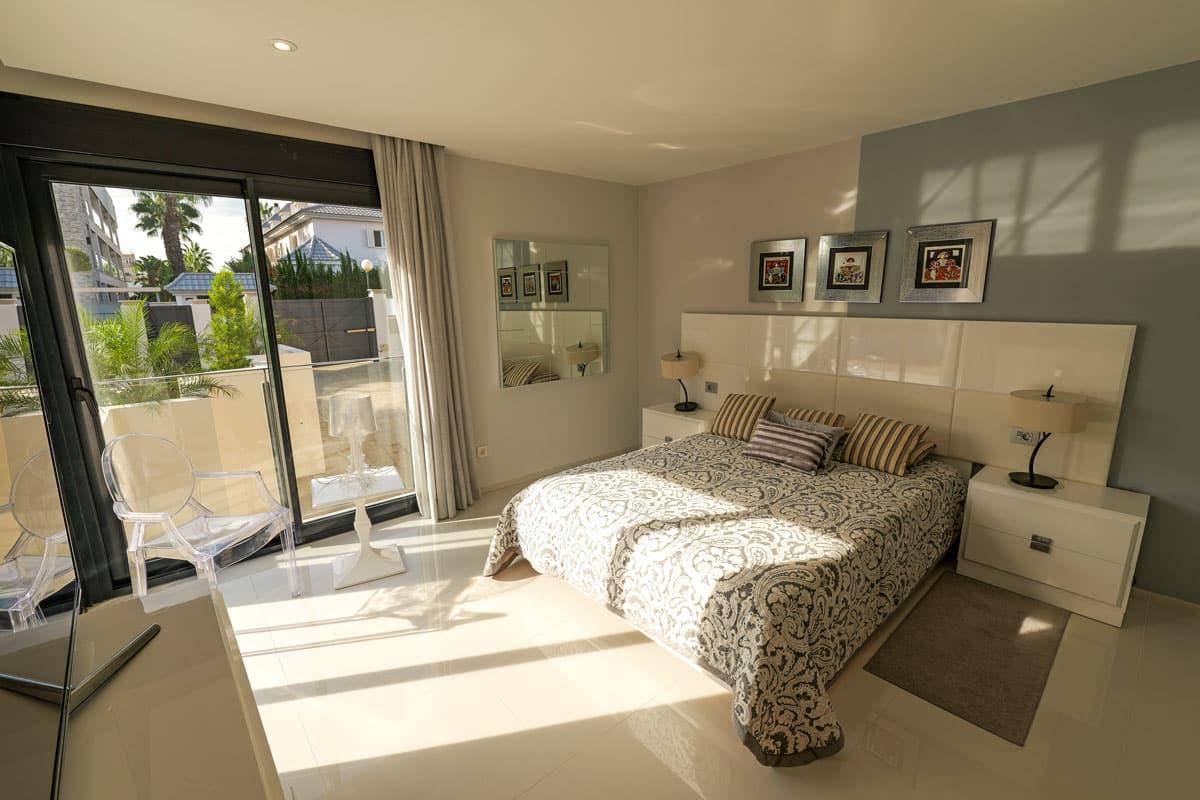 Sonniges Schlafzimmer mit Fliesenboden, großem Bett und direktem Zugang zum Balkon.