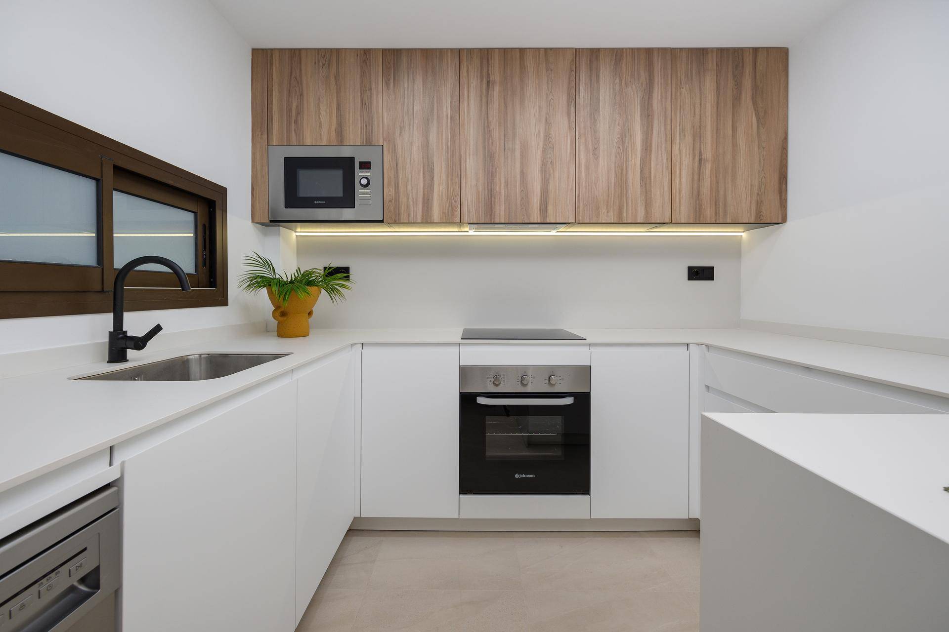 Moderne Küche mit weißen Unterschränken, Holz-Oberschränken und integrierten Geräten.
