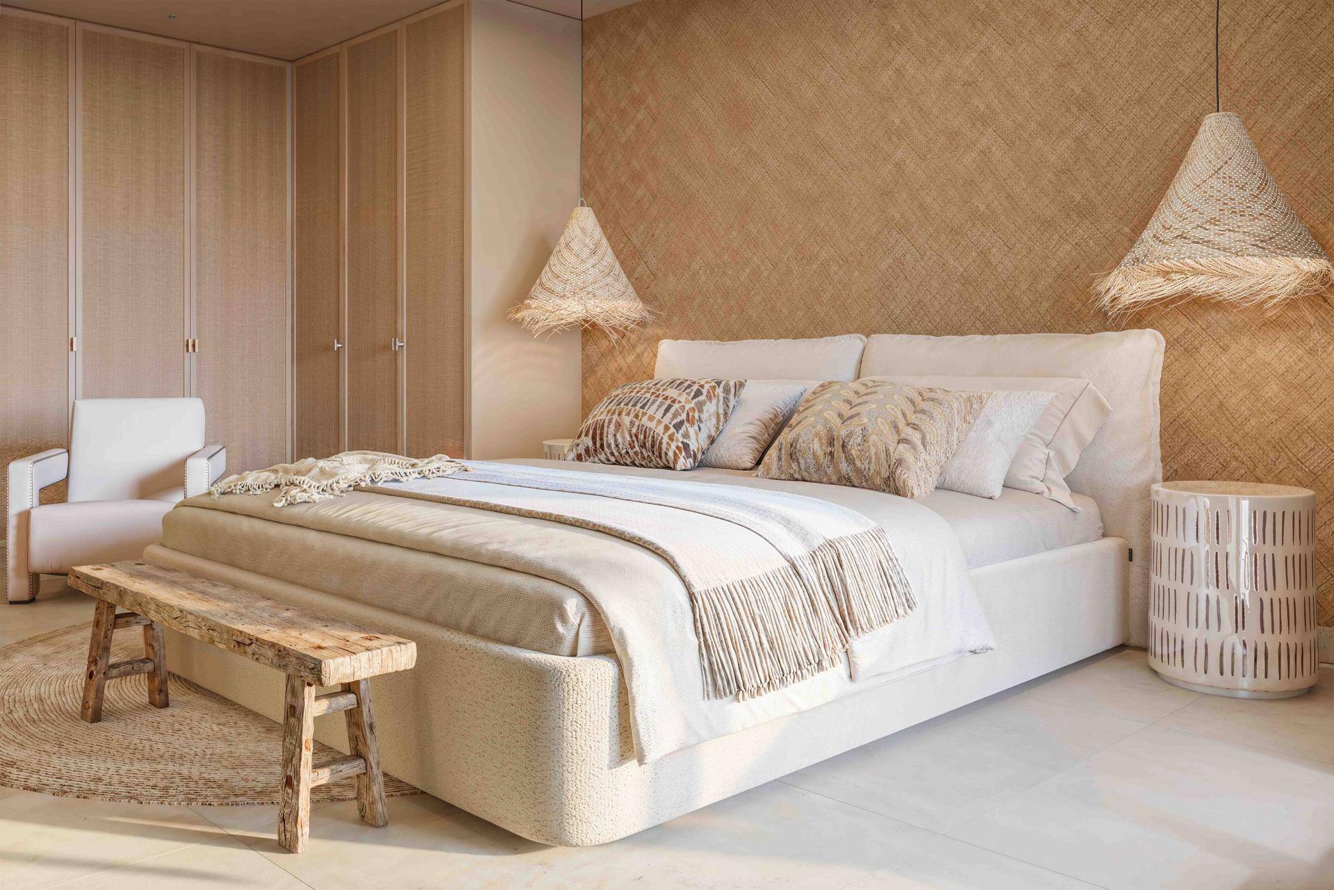 Modernes Schlafzimmer mit bequemen Möbeln, strukturierten Wänden und viel Tageslicht.