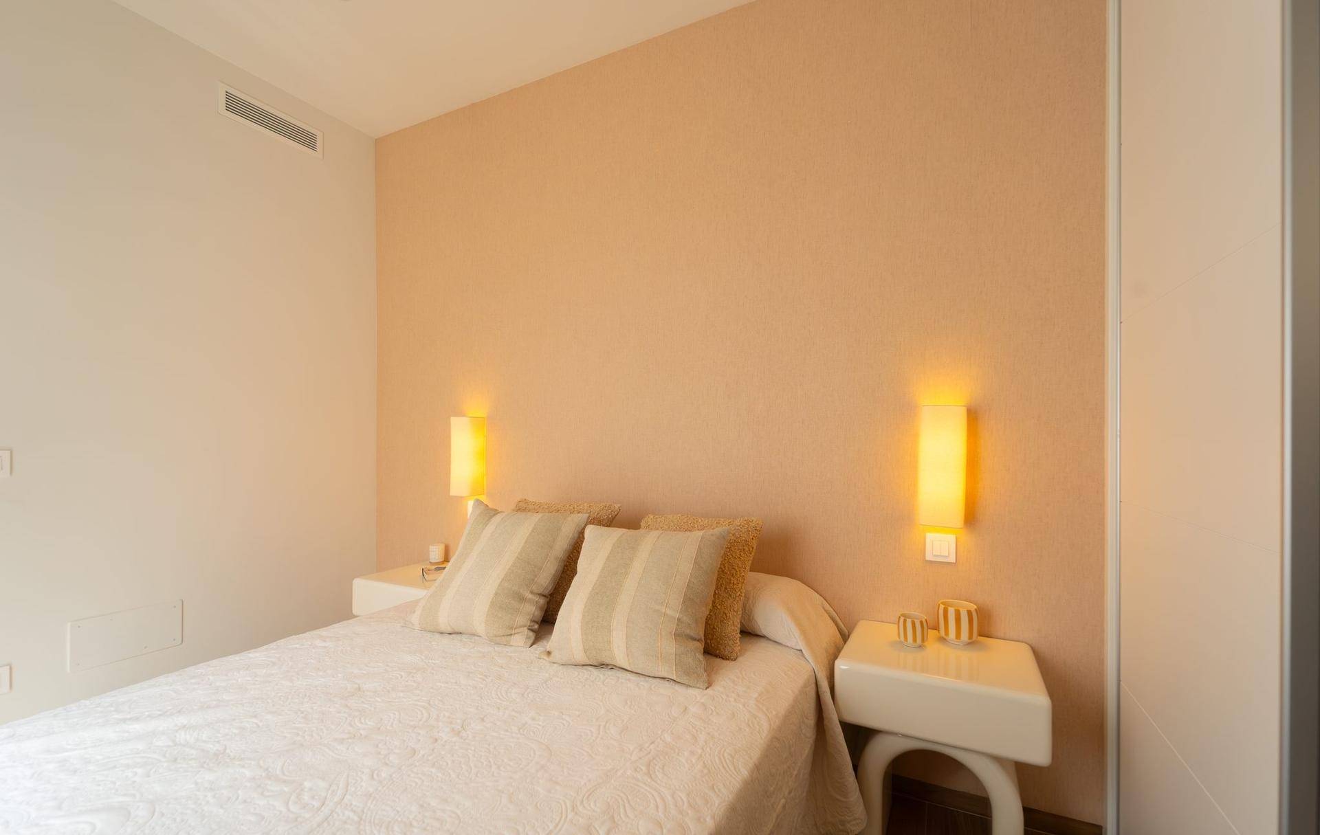 Ruhiges Schlafzimmer mit Doppelbett, beigefarbenen Wänden und indirekter Beleuchtung.