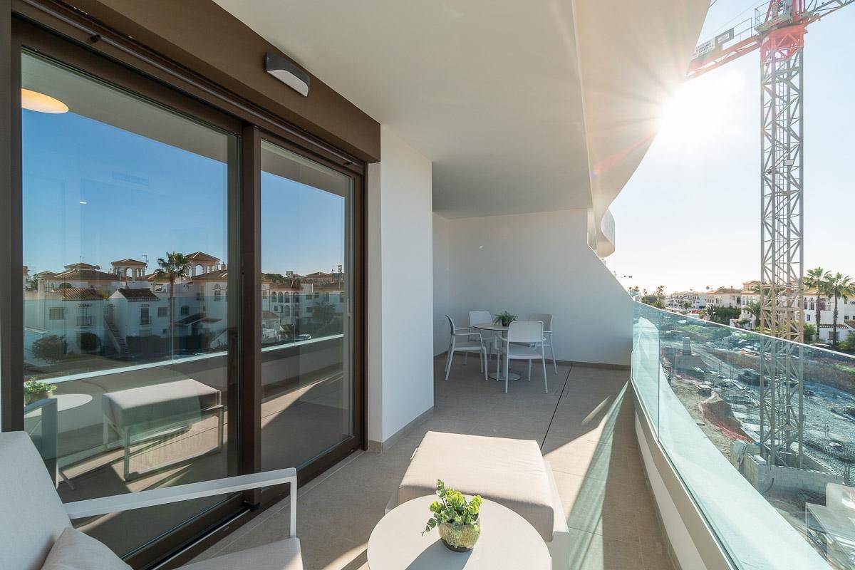 Geräumiger Balkon mit Ess- und Lounge-Bereich, Glasgeländer und sonnigem Ausblick.