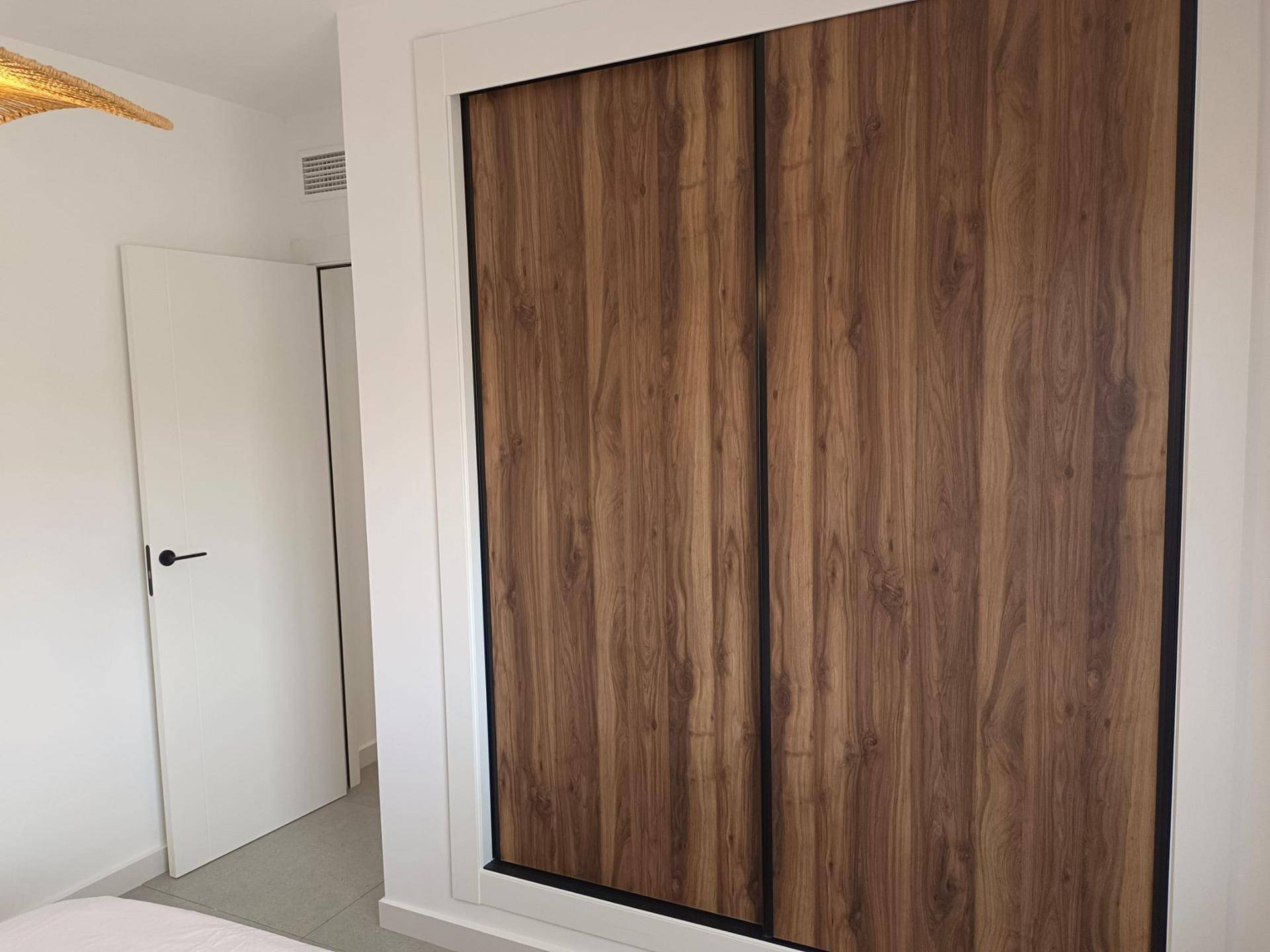Moderner Einbauschrank mit Holzfronten in einem hellen Schlafzimmer.
