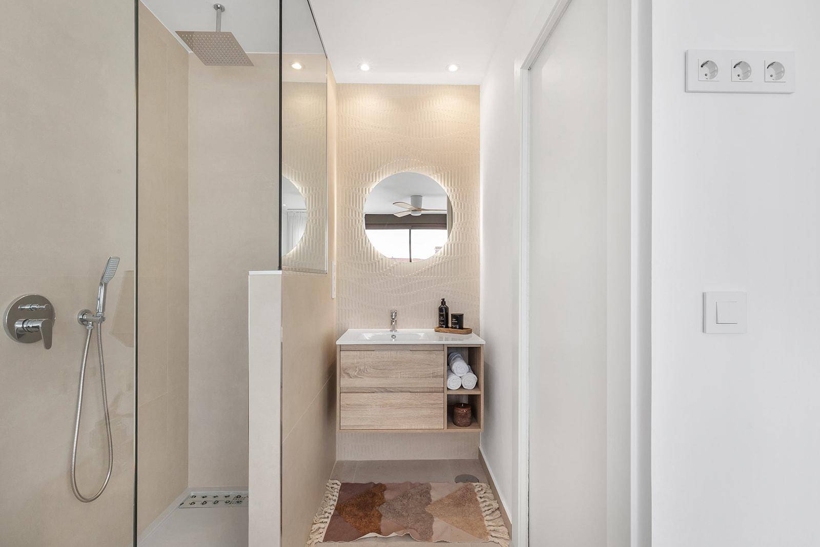 Modernes Badezimmer mit begehbarer Dusche, beleuchtetem Spiegel und Holzwaschtisch.