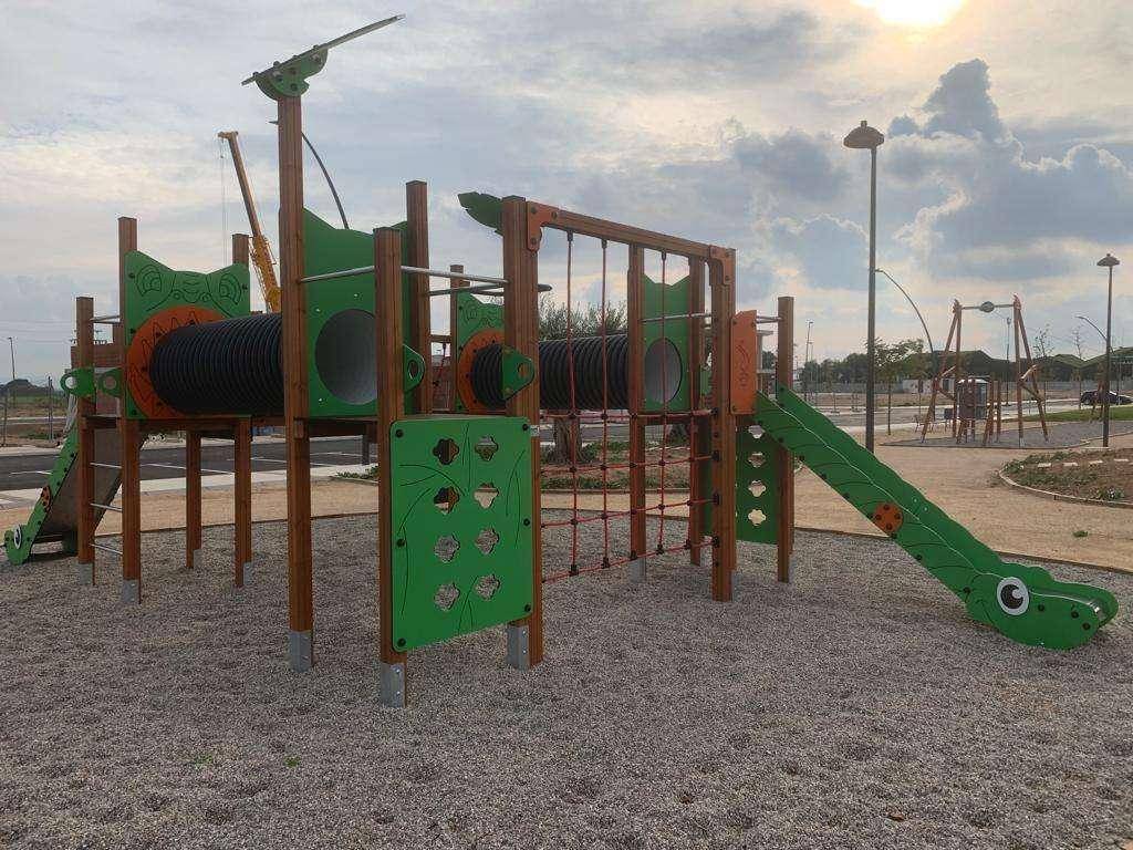 Bunter Spielplatz mit Klettertunneln, Rutschen und Sandbereich für Kinder.