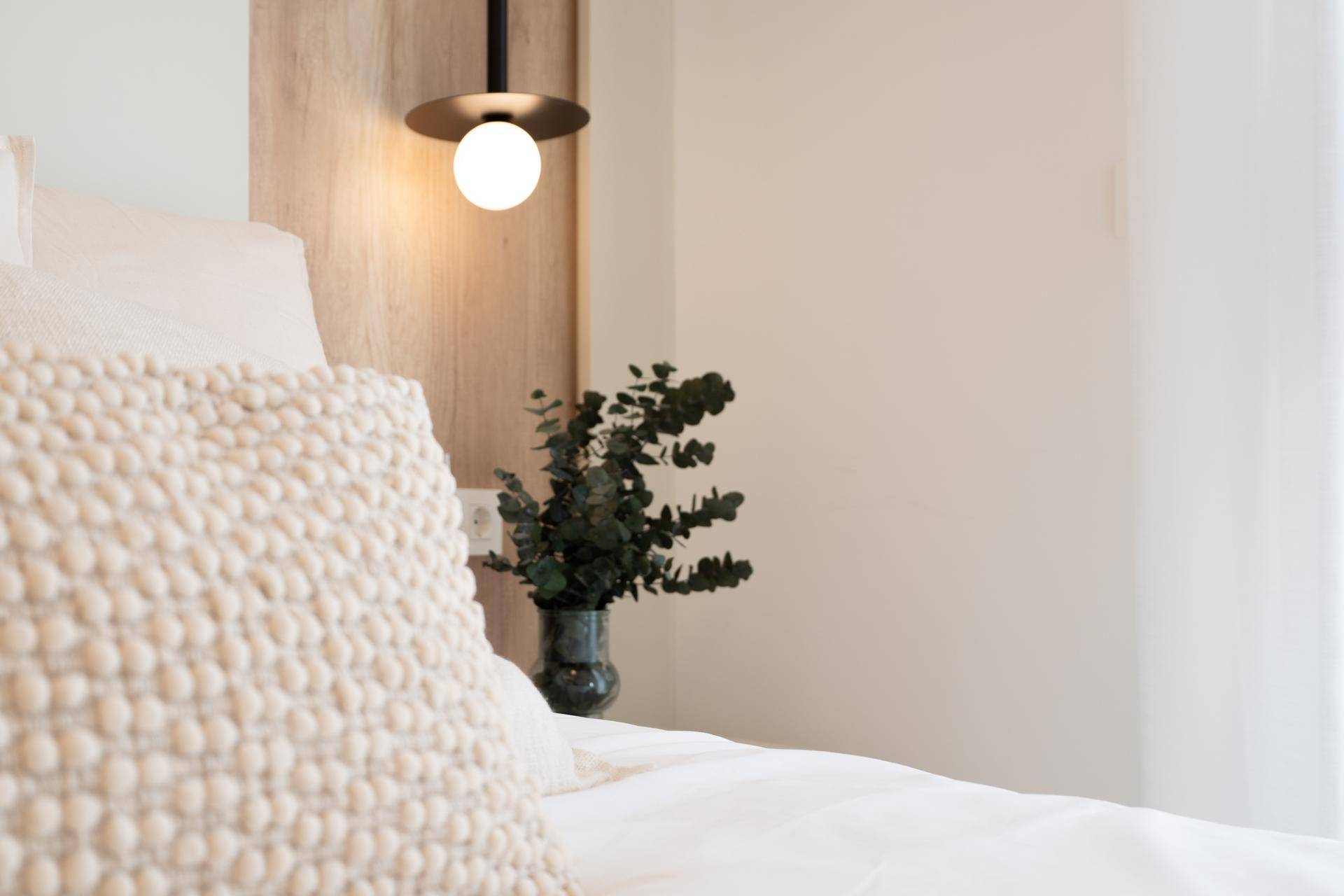 Detailansicht des Nachttisches mit Beleuchtung und Dekoration im modernen Schlafzimmer.
