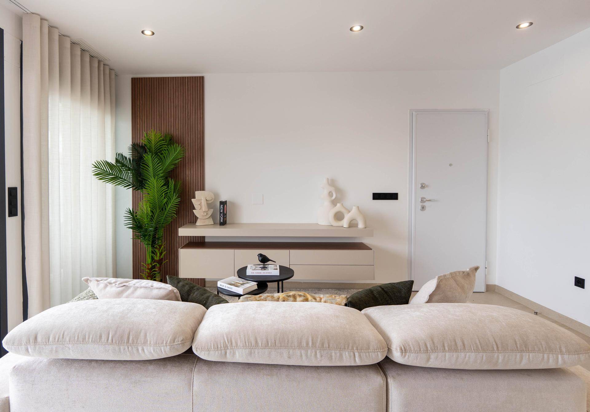 Gemütlicher Wohnbereich mit beigem Sofa, Holzwandakzent und moderner Dekoration.