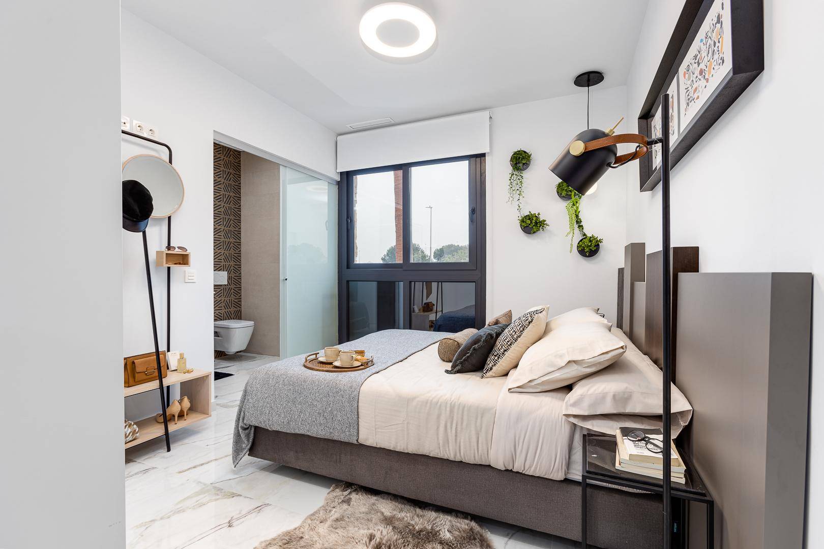 Modernes Schlafzimmer mit Doppelbett, großem Fenster und angrenzendem Badezimmer.