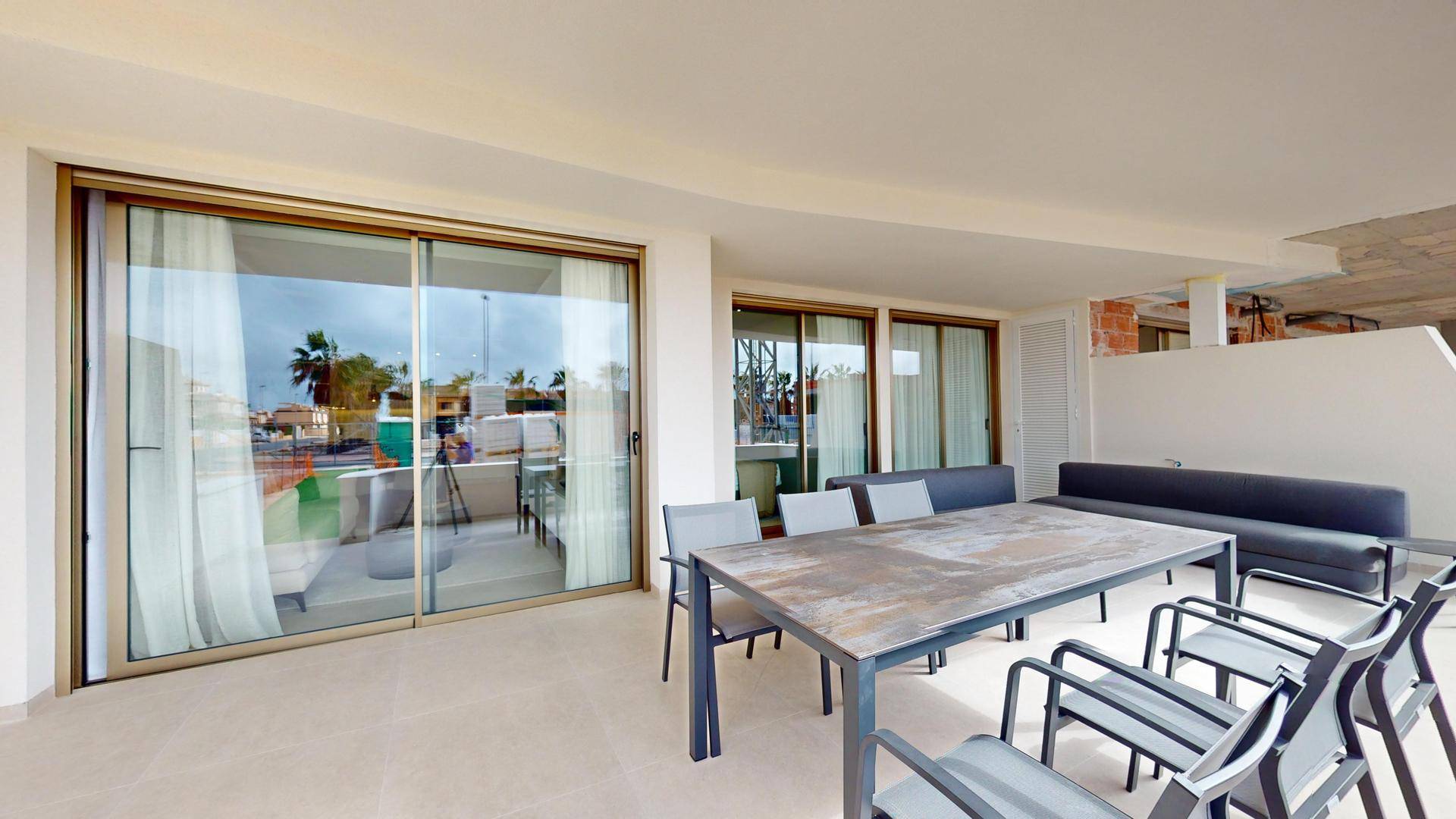 Große überdachte Terrasse mit Esstisch und Loungesofa, perfekt für Mahlzeiten im Freien.