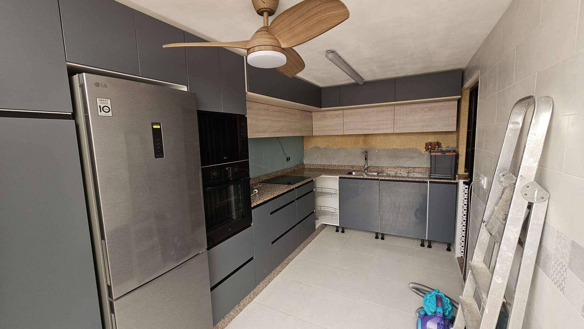 Küche in Renovierung mit neuen Schränken, Geräten und Deckenventilator.