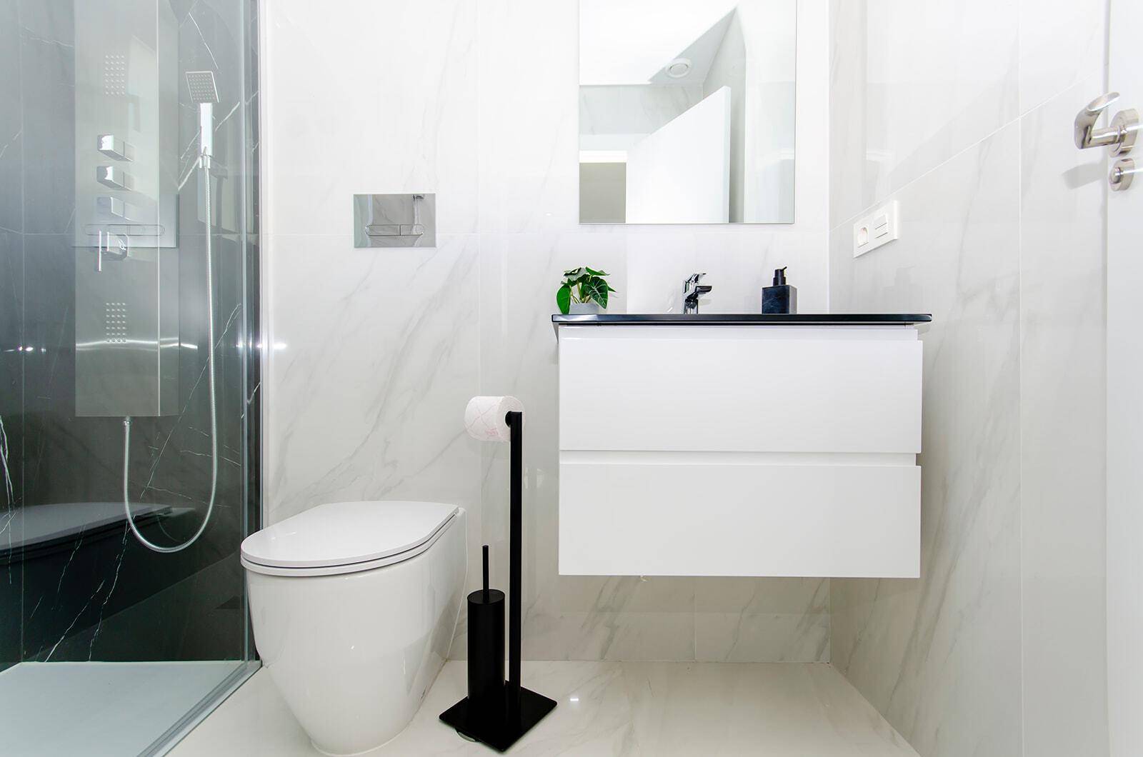 Modernes Badezimmer mit Duschkabine, wandhängendem WC und eleganten Fliesen.