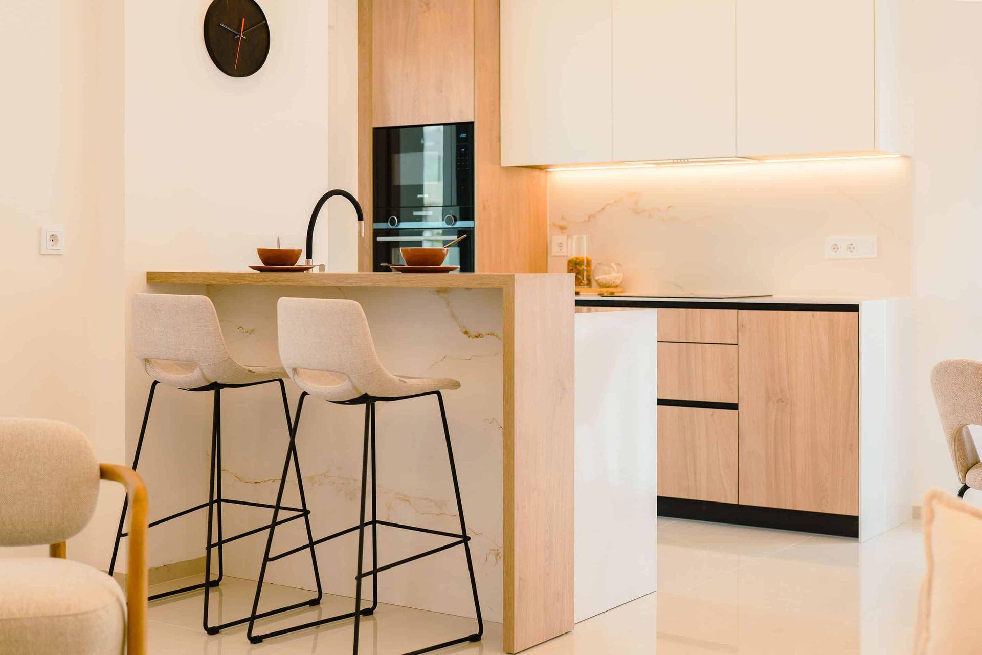 Stilvolle Küche mit Frühstücksbar, integriertem Backofen und modernen Holzfronten.