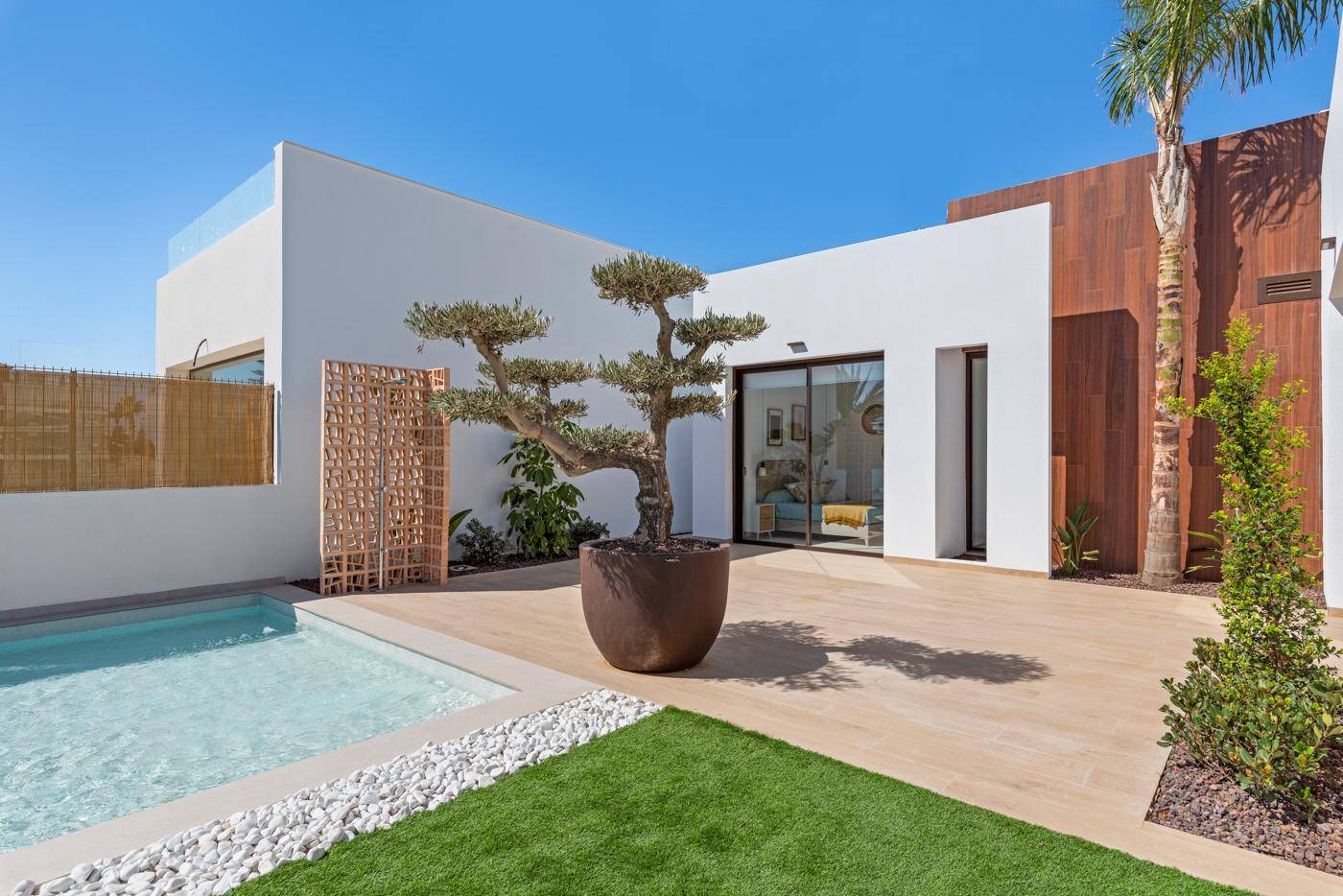 Sonniger Außenbereich mit Pool, gepflegtem Rasen und moderner Villenarchitektur.