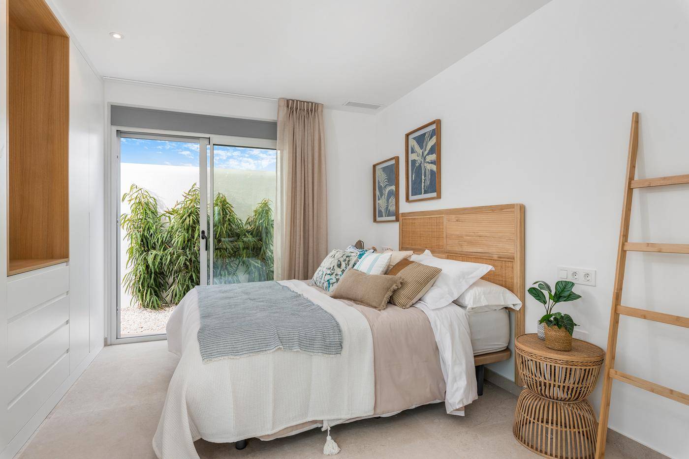 Helles Schlafzimmer mit Einbauschränken und Schiebetür zum privaten Gartenbereich.