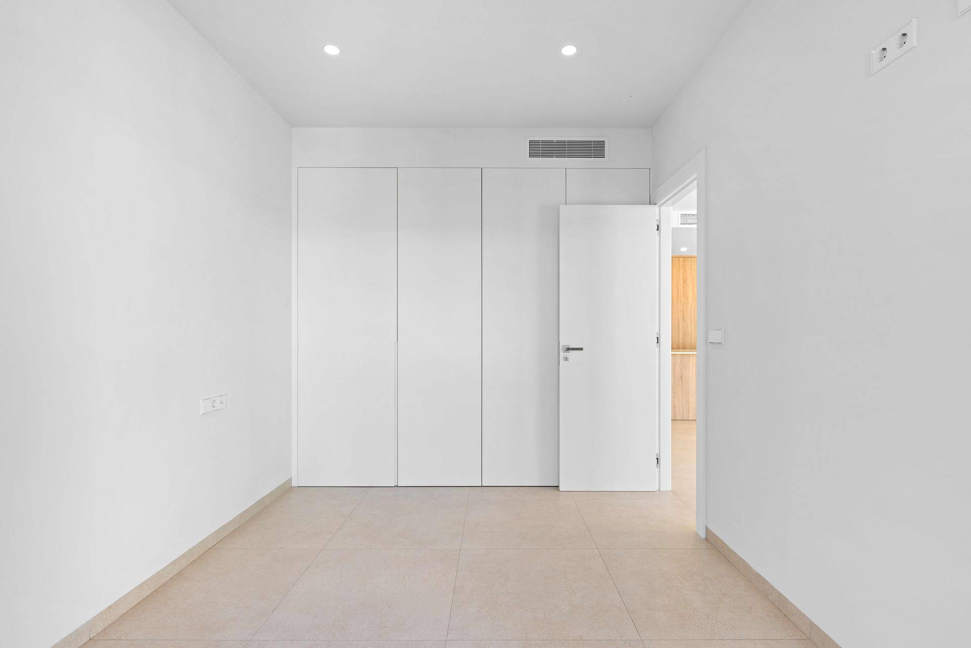 Helles Schlafzimmer mit integrierten Kleiderschränken und neutralem Fliesenboden.