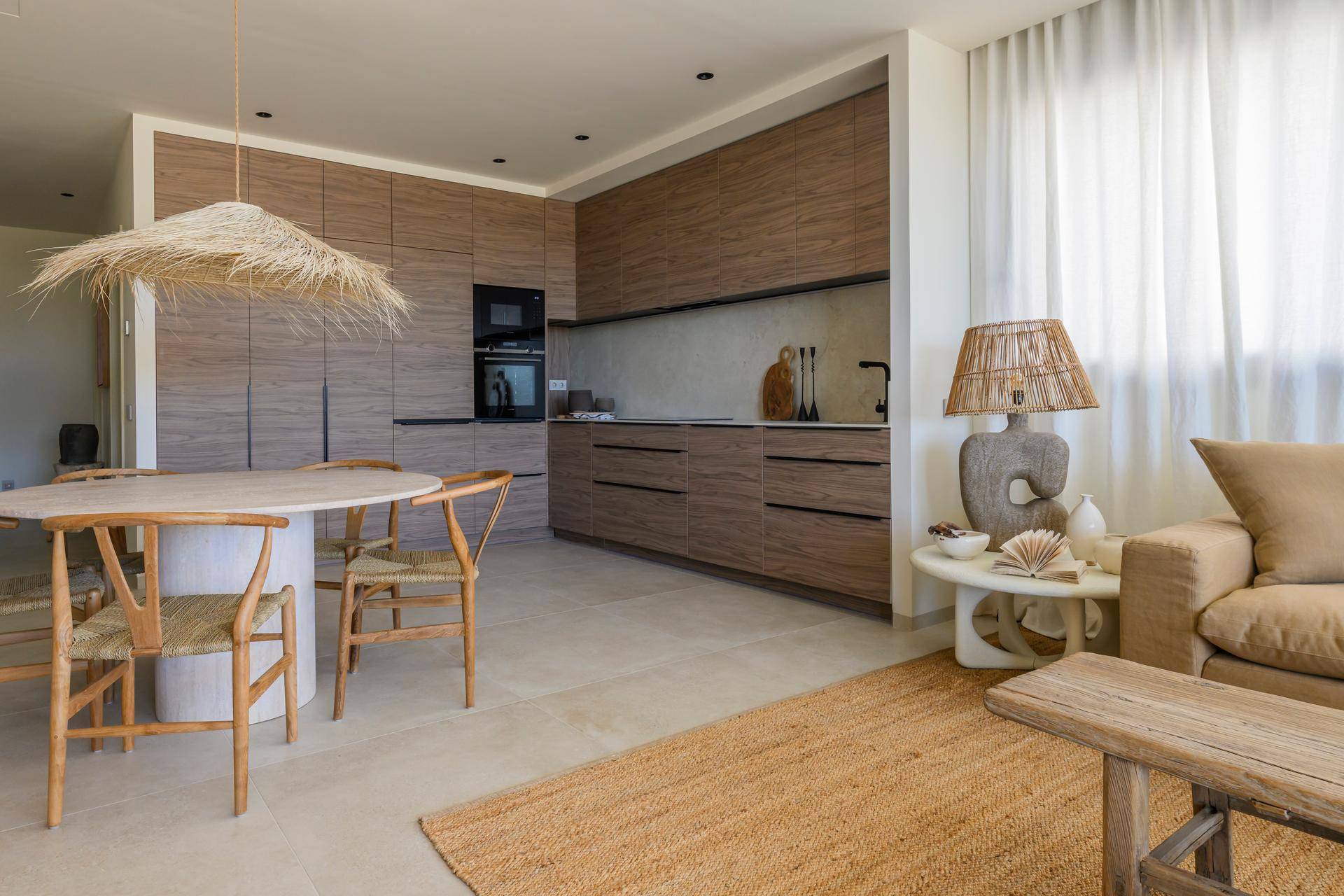 Heller Wohn-Essbereich mit Holzküche, rustikalem Esstisch und gemütlichem Sofa in warmen Farbtönen.
