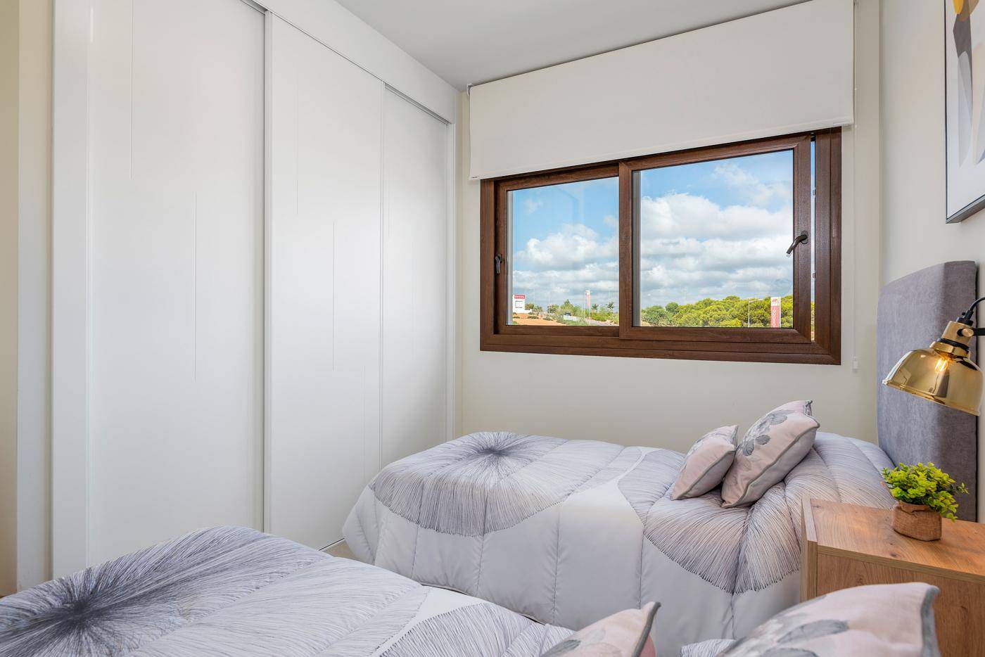 Gemütliches Schlafzimmer mit zwei Einzelbetten, Einbauschränken und einem Fenster mit Blick ins Grüne.