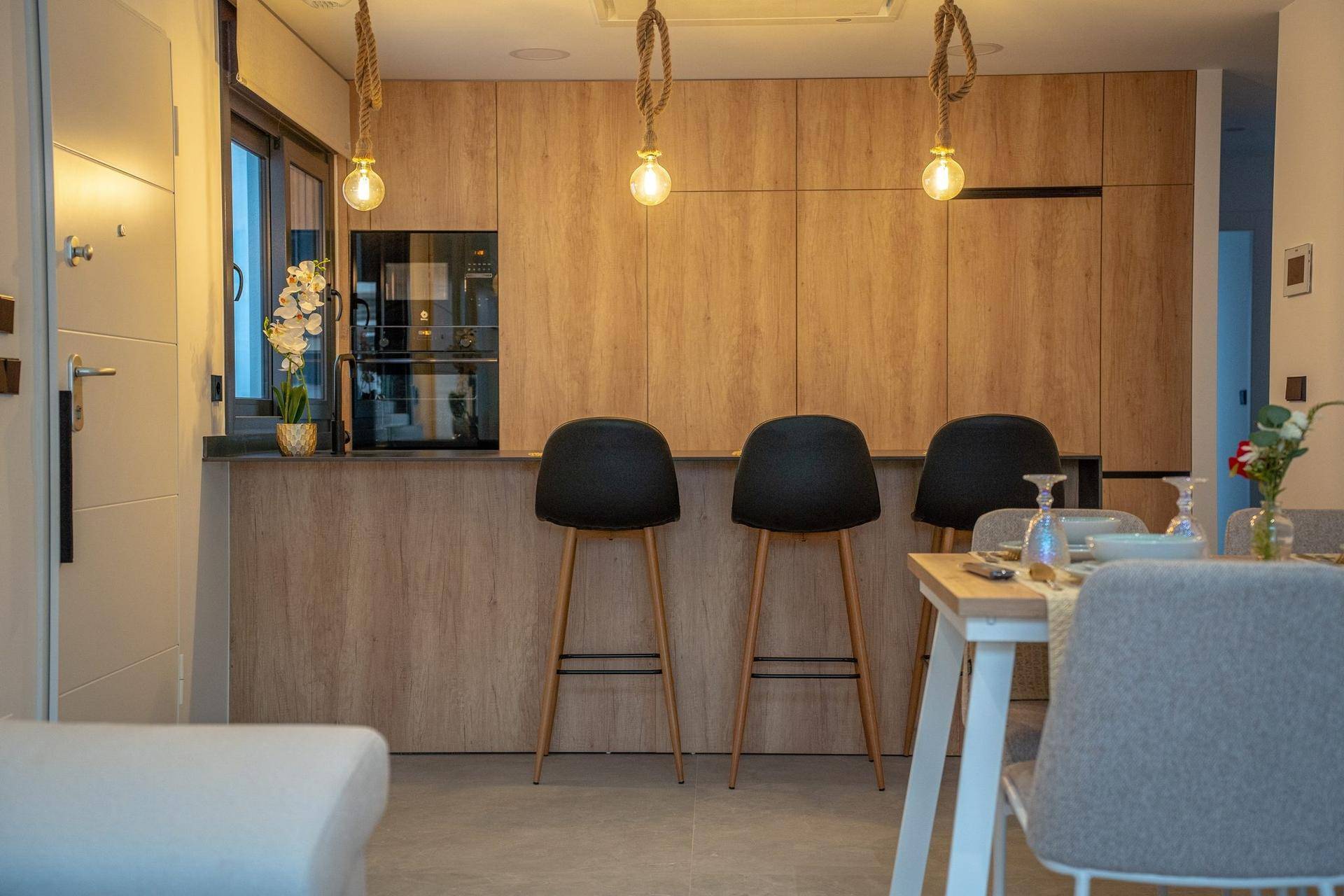 Moderne Holzküche mit integrierten Geräten, Barhockern und Essbereich.