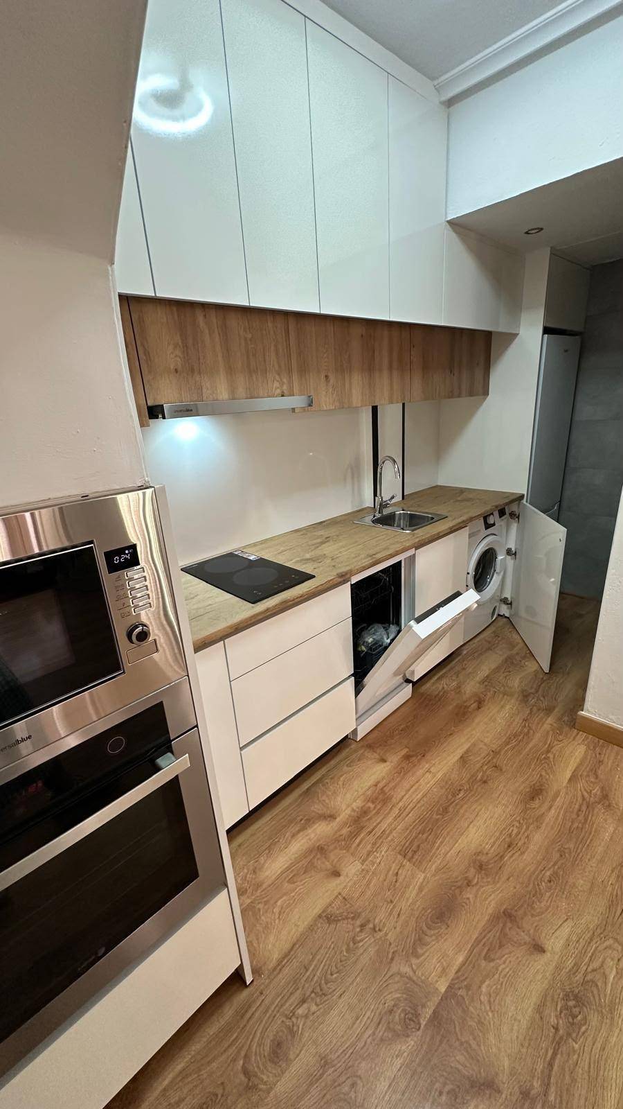 Moderne Küche mit integriertem Geschirrspüler und Waschmaschine, Holzboden.