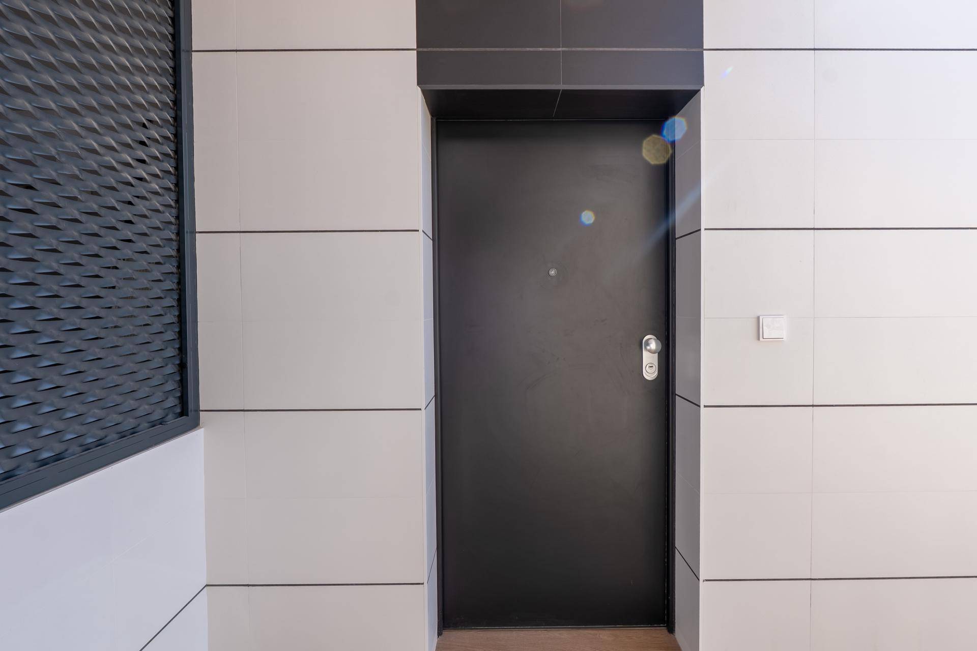 Moderne Eingangstür in dunklem Anthrazit, umgeben von weißen und grauen Fassadenplatten.