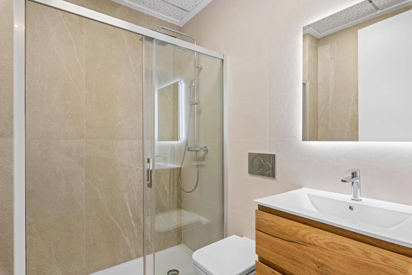 Helles Badezimmer mit begehbarer Dusche, modernem Waschtisch und großem Spiegel.