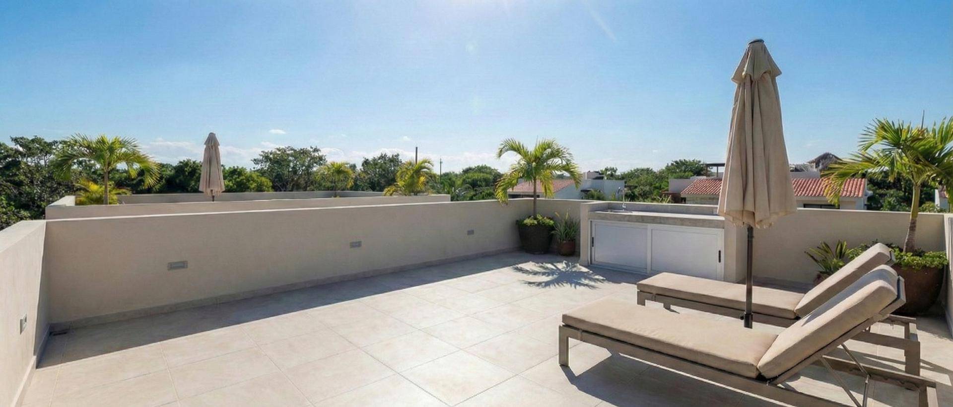Geräumige Dachterrasse mit Fliesenboden, Sonnenliegen und Sonnenschirm, ideal zum Entspannen.