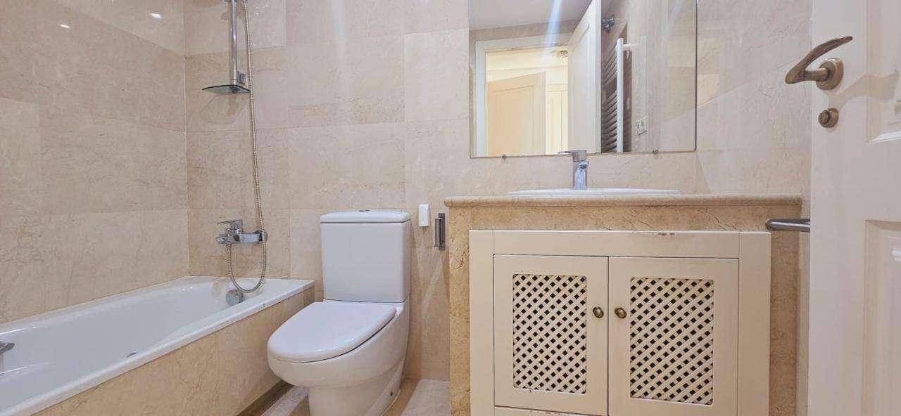 Modernes Badezimmer mit Badewanne, WC und Waschtischunterschrank, komplett gefliest.