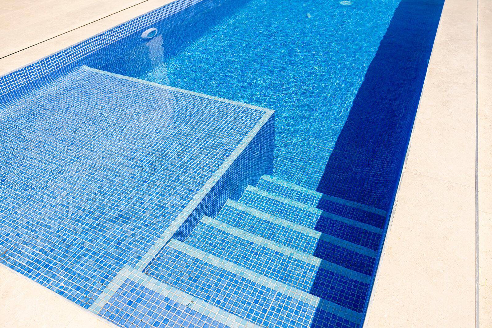 Detailansicht des Pools mit blauen Mosaikfliesen und breiten Einstiegsstufen.