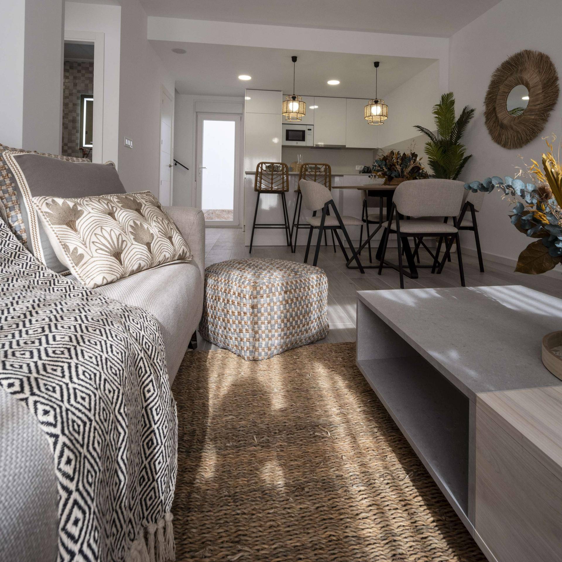 Heller offener Wohn-Essbereich mit moderner Küche und gemütlichem Sofa.