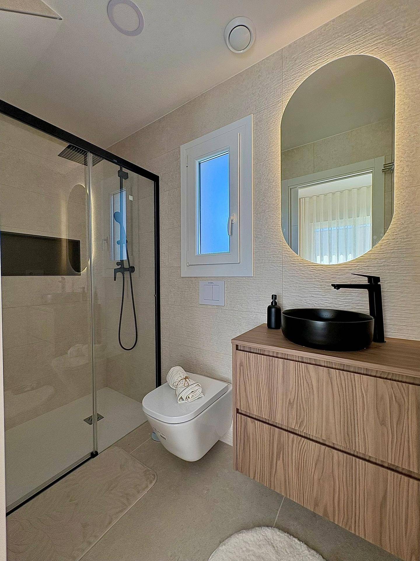 Helles Badezimmer mit begehbarer Dusche, Holzwaschtisch und beleuchtetem Spiegel, modern gestaltet.