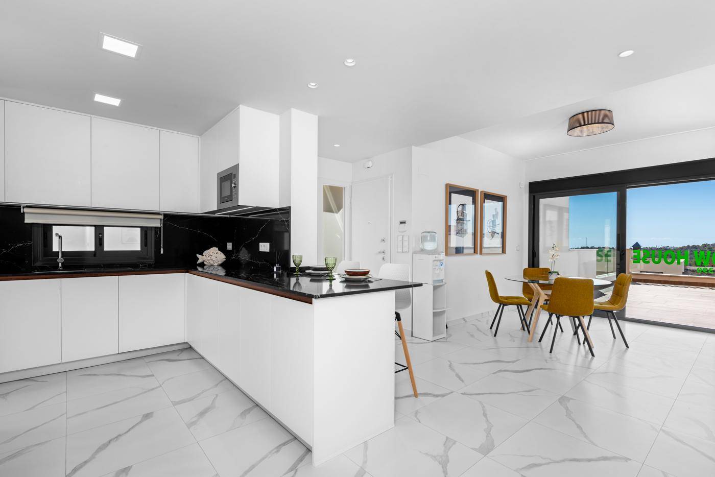 Offene Küche mit Essbereich, modernen Möbeln und Zugang zur Terrasse.