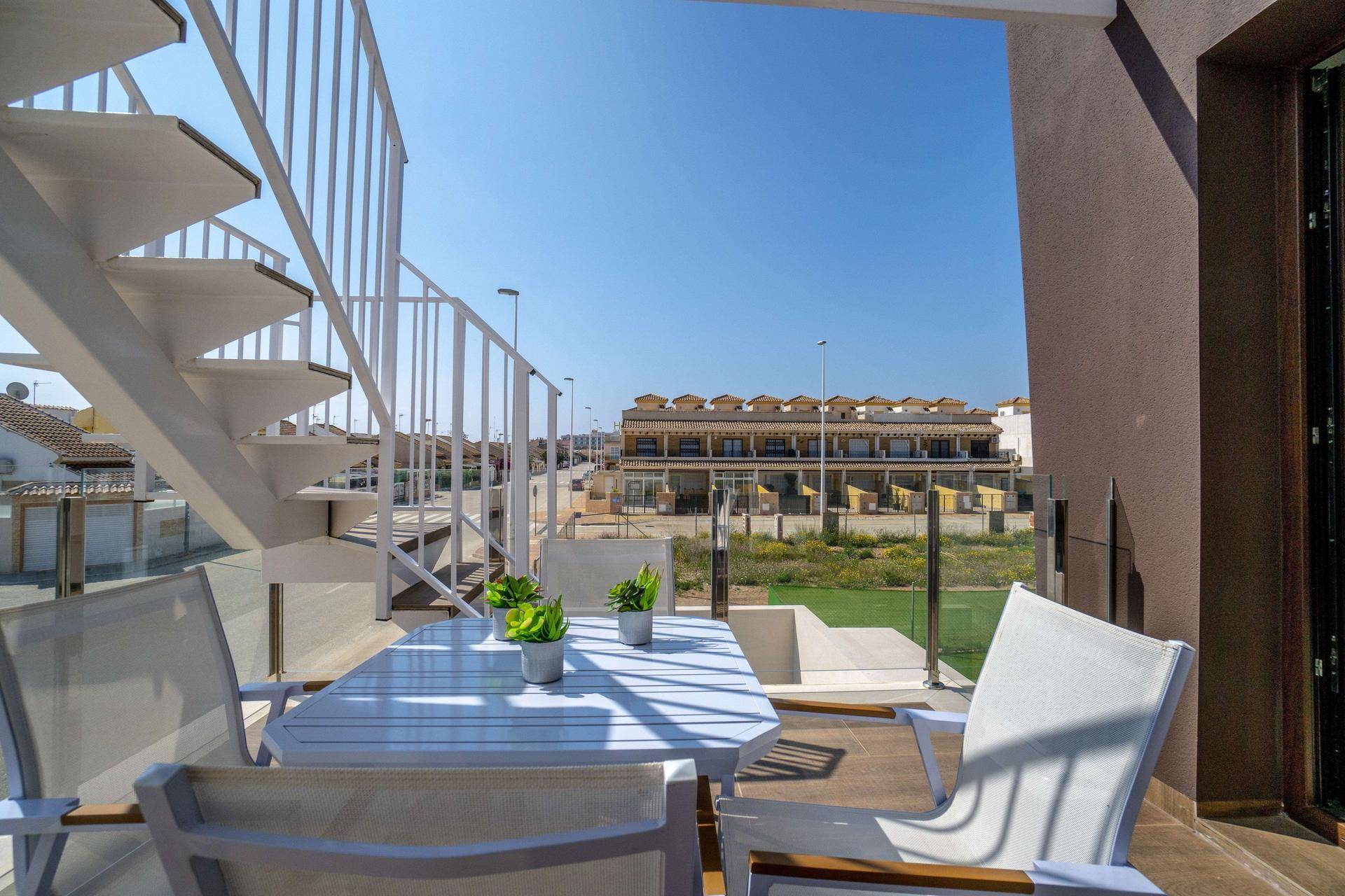Sonniger Balkon mit modernen Gartenmöbeln und Blick auf die umliegende Wohnsiedlung.