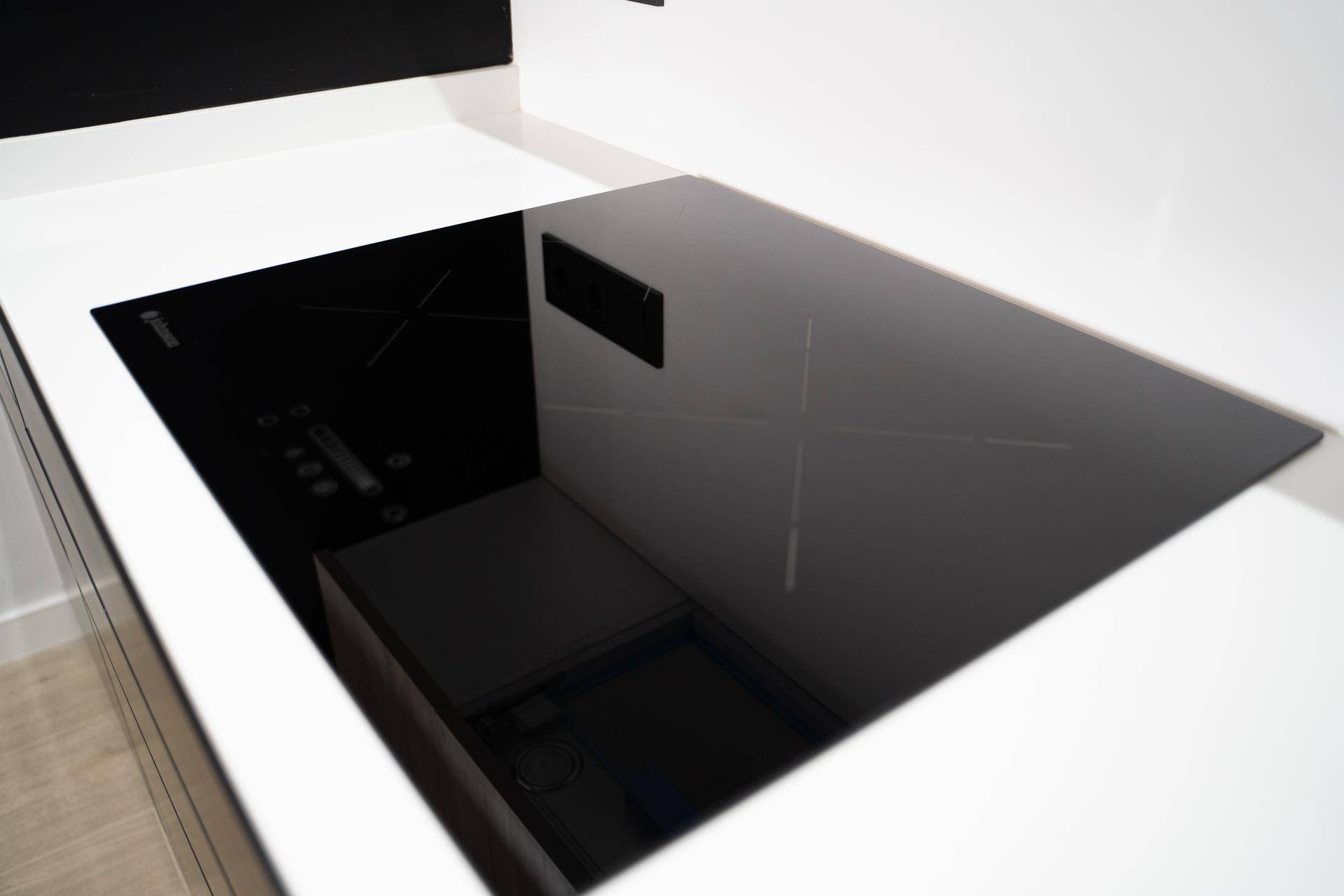 Moderne Induktionskochplatte in einer minimalistischen Küche mit weißen Arbeitsplatten.