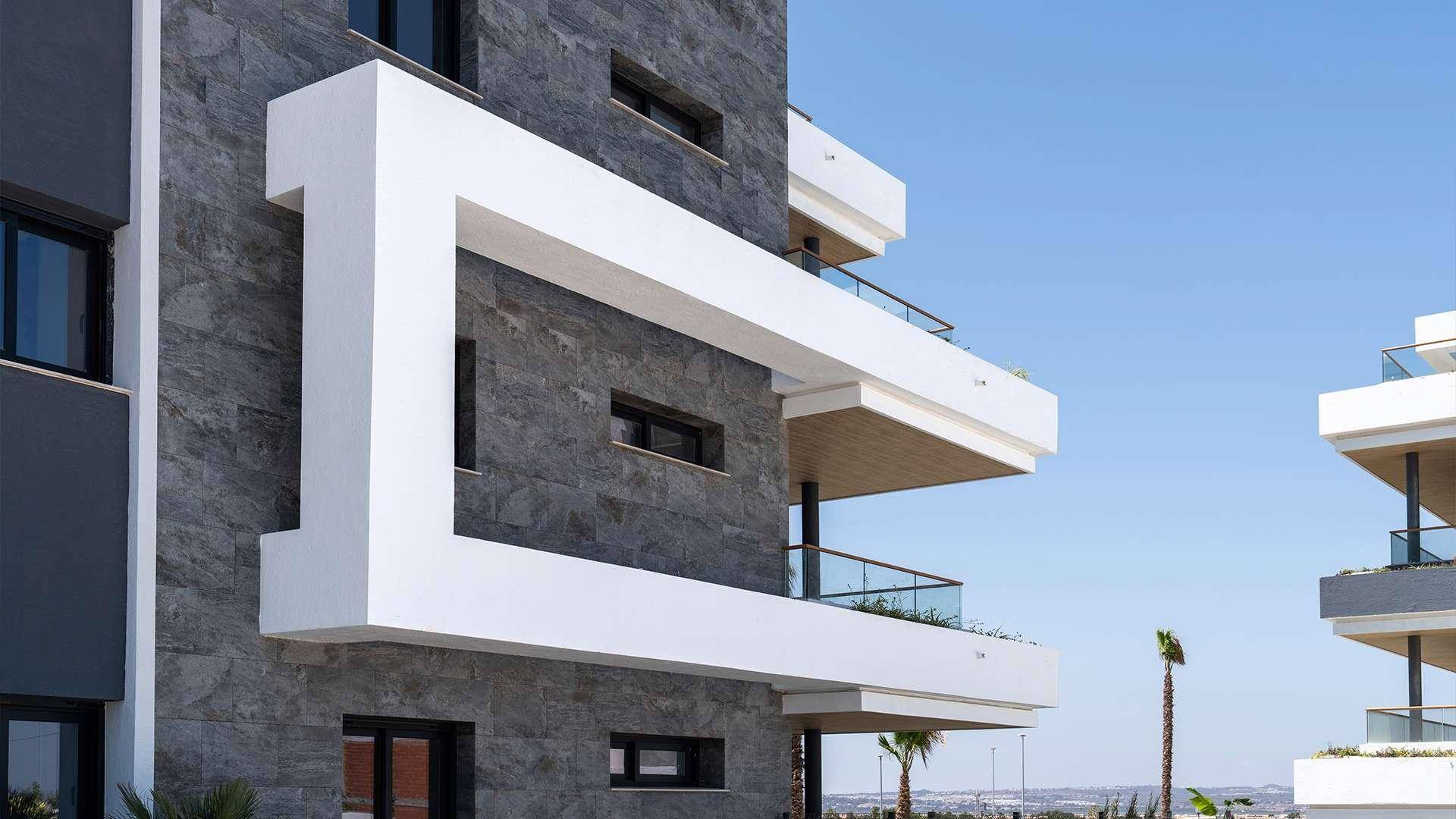 Fassadendetail eines modernen Gebäudes mit dunkler Steinverkleidung und markanten weißen Rahmen.