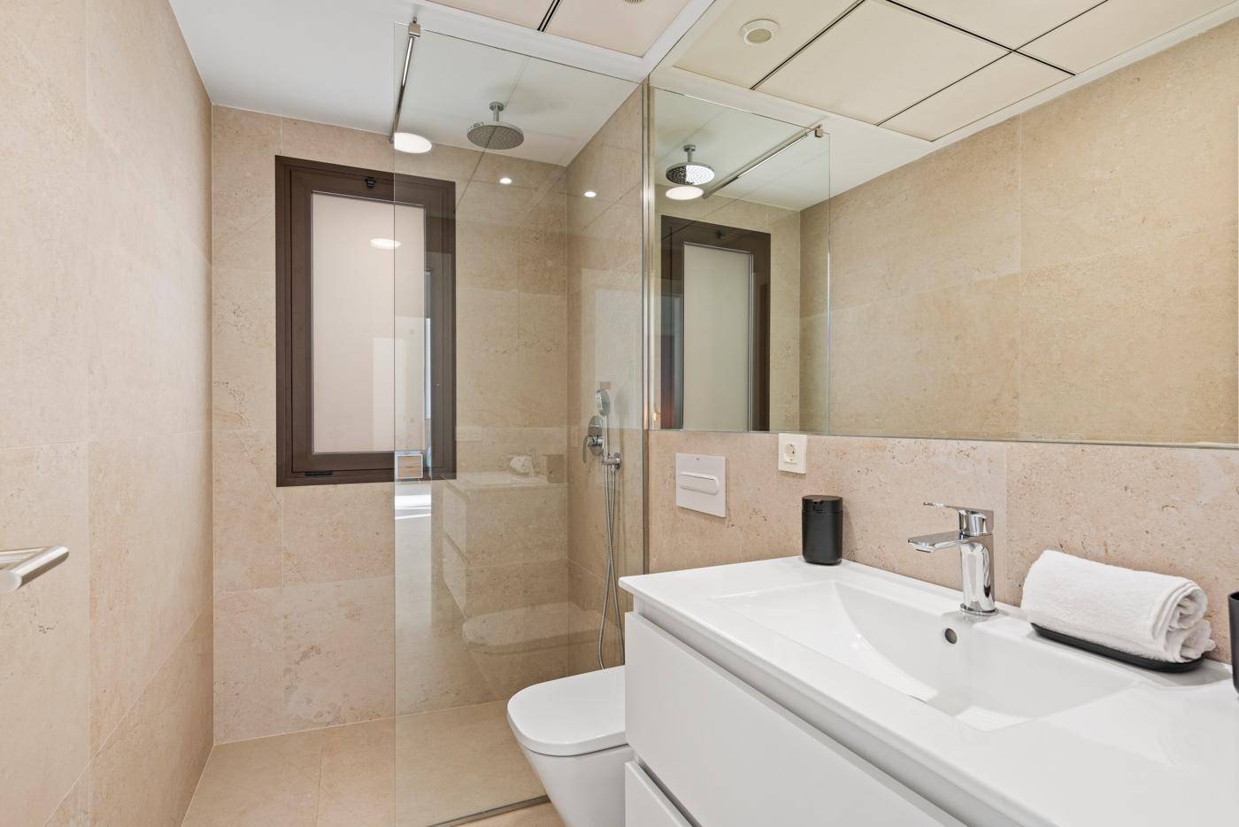 Modernes Badezimmer mit begehbarer Dusche, beigefarbenen Fliesen und großem Spiegel.