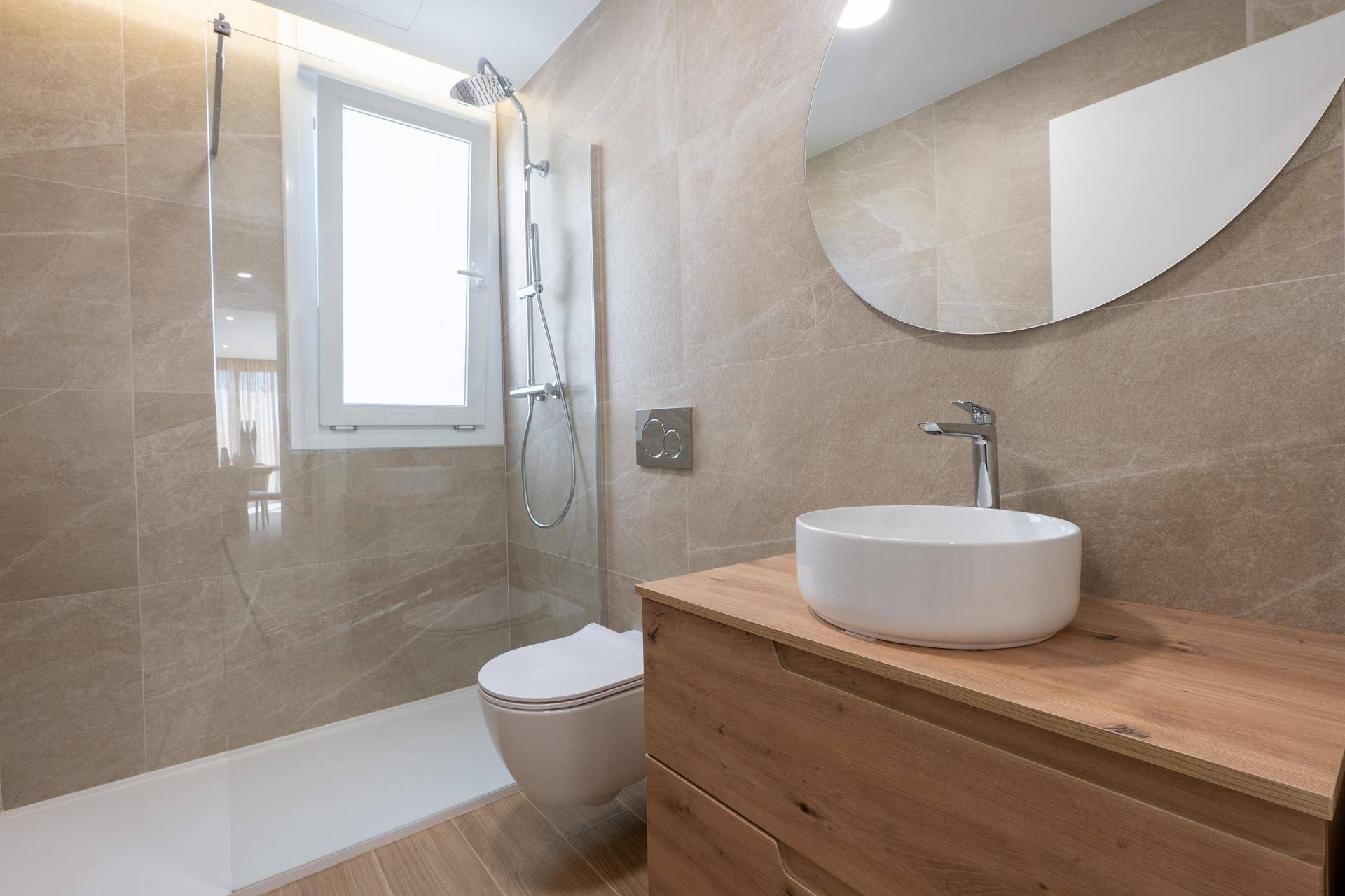 Modernes Badezimmer mit begehbarer Dusche, Holzwaschtisch und Fenster für natürliches Licht.