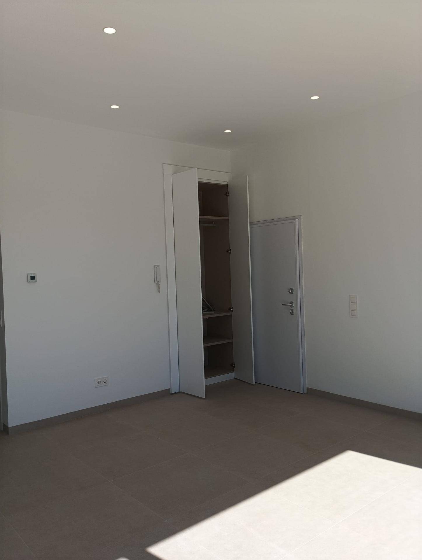 Helles Schlafzimmer mit Einbauschrank, hellem Boden und direkter Tür zum Flur.