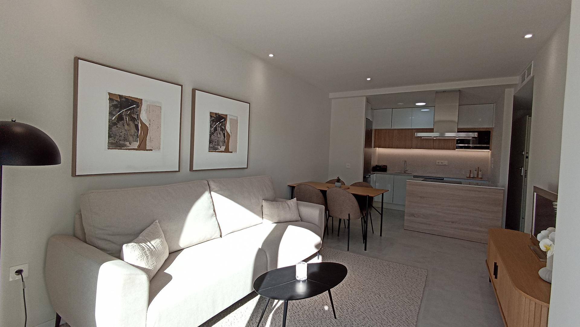 Gemütlicher Wohnbereich mit Sofa, Esstisch und Blick auf die offene Küche.