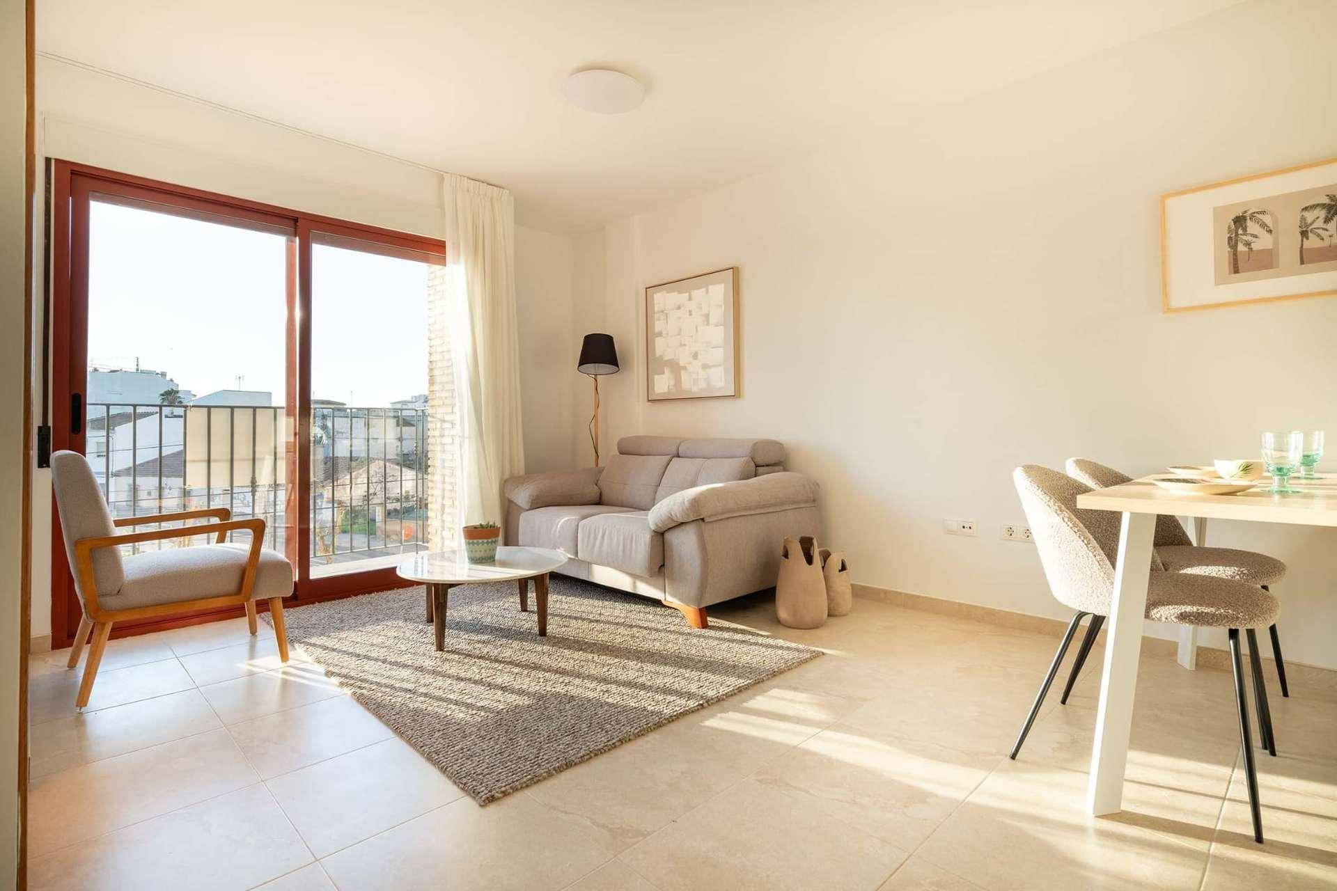Helles Wohn-Esszimmer mit Fliesenboden, beigem Sofa und Zugang zu einem französischen Balkon.