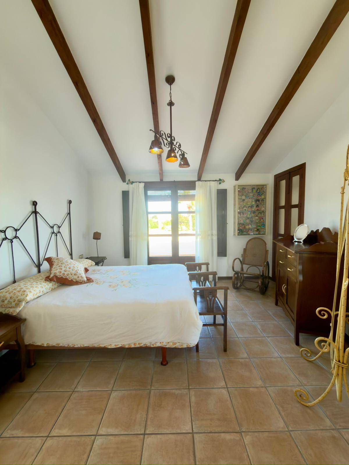Geräumiges Schlafzimmer mit Doppelbett, sichtbaren Holzbalken und traditionellen Möbeln.