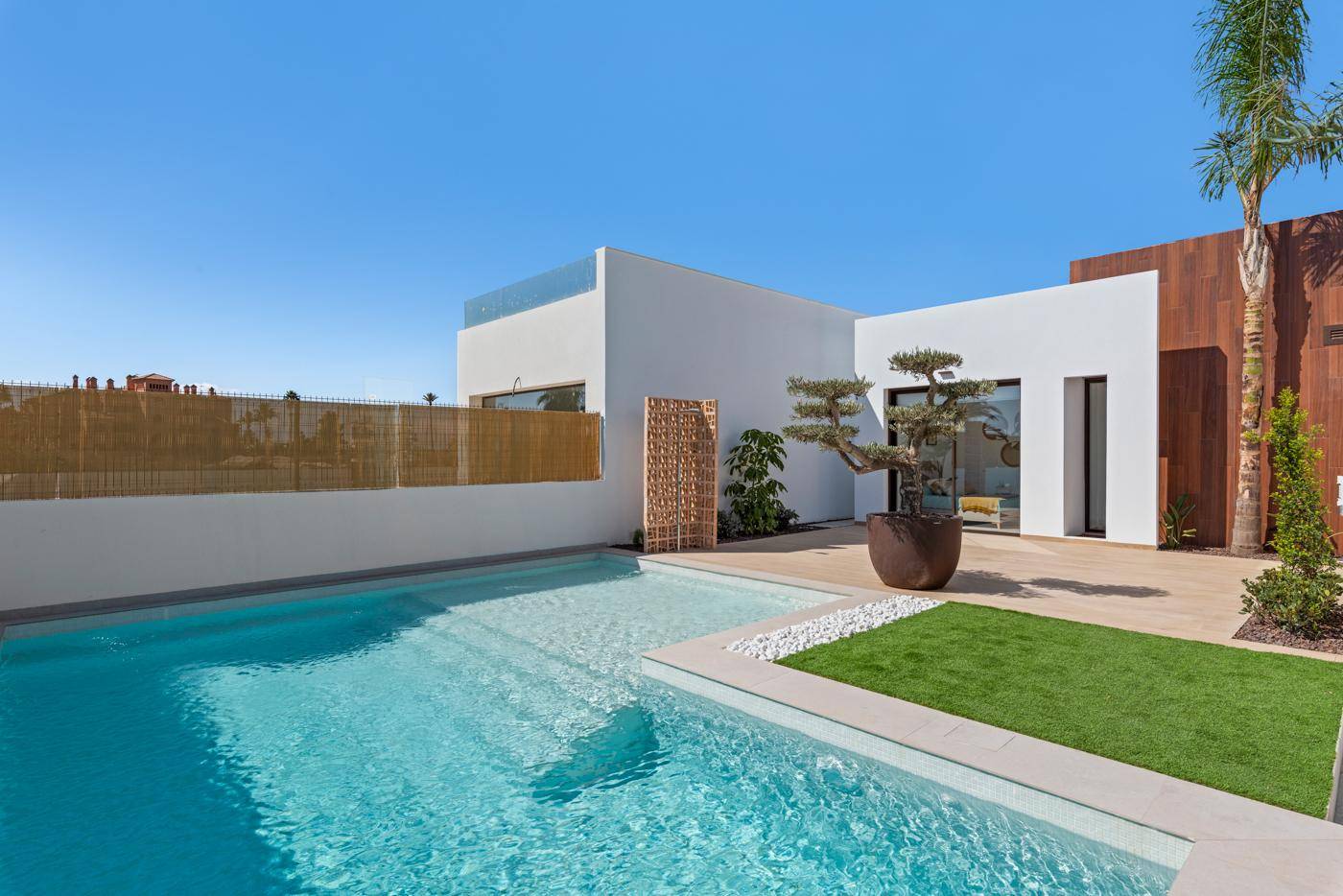 Blick auf den privaten Poolbereich und die moderne Architektur der Villa unter blauem Himmel.