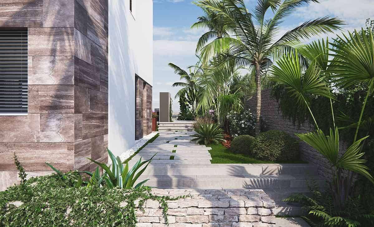 Geschwungener Gartenweg mit Steinstufen, üppiger tropischer Bepflanzung und Palmen neben der Villa.