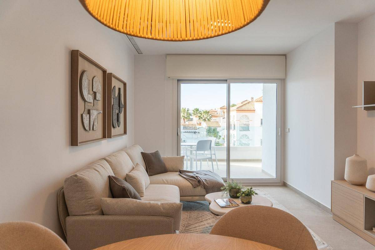 Gemütliches Wohnzimmer mit Sofa, Couchtisch und großen Schiebetüren zum sonnigen Balkon.