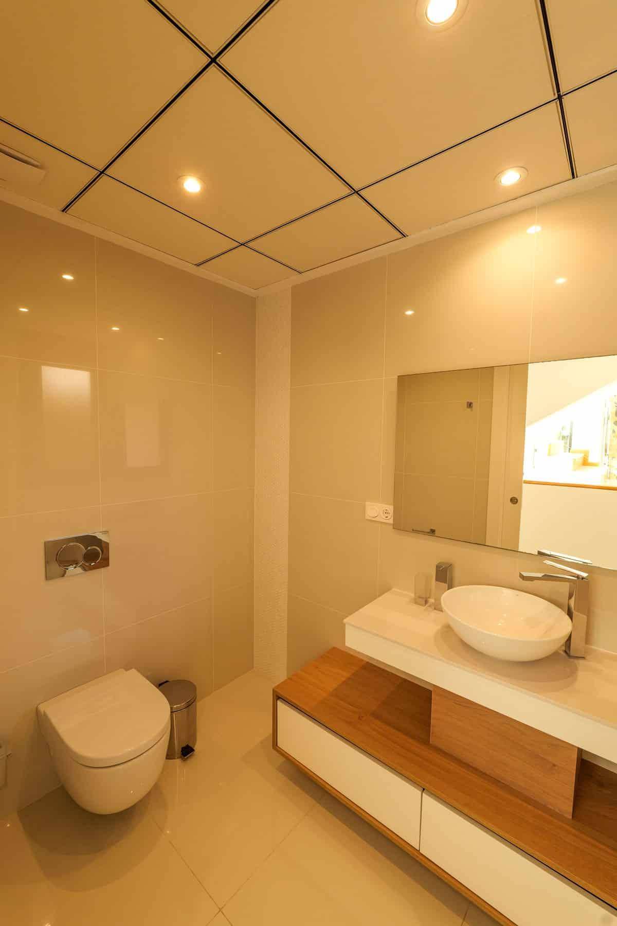 Modernes Gäste-WC mit Wand-WC, Aufsatzwaschbecken und eleganten Fliesen.