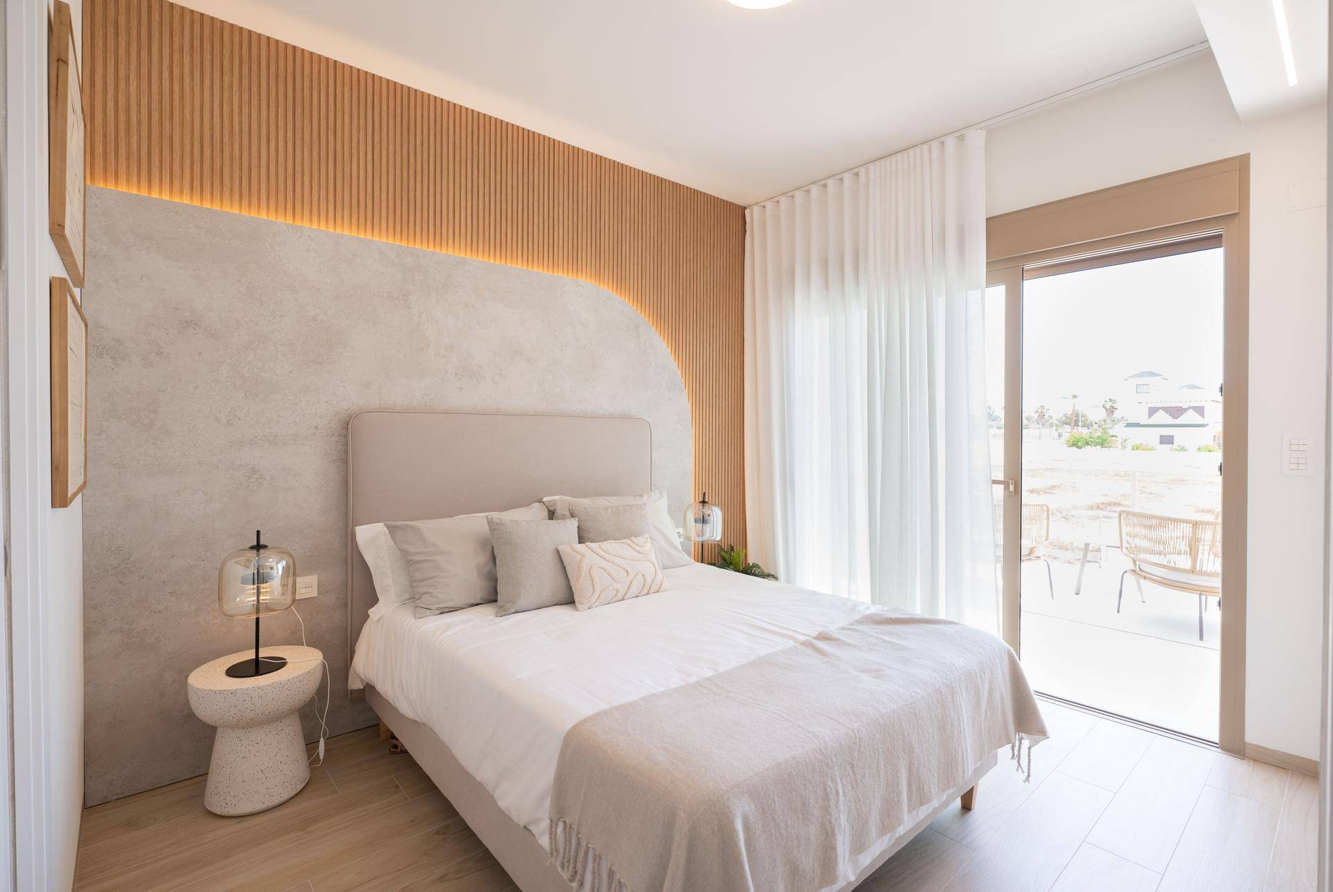 Modernes Schlafzimmer mit Holzwand, beigem Kopfteil und Zugang zu einem Balkon.
