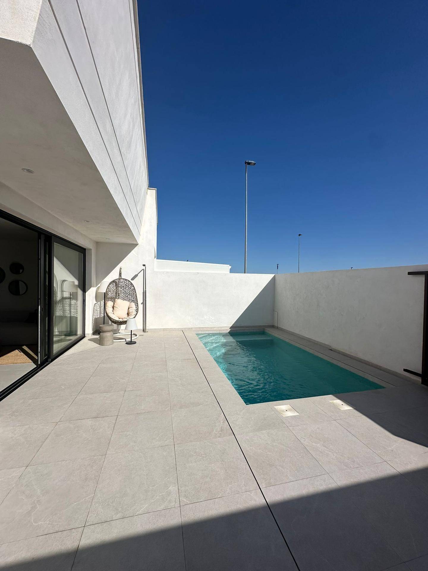 Privater Poolbereich mit gefliester Terrasse und Hängesessel neben der modernen Villa.